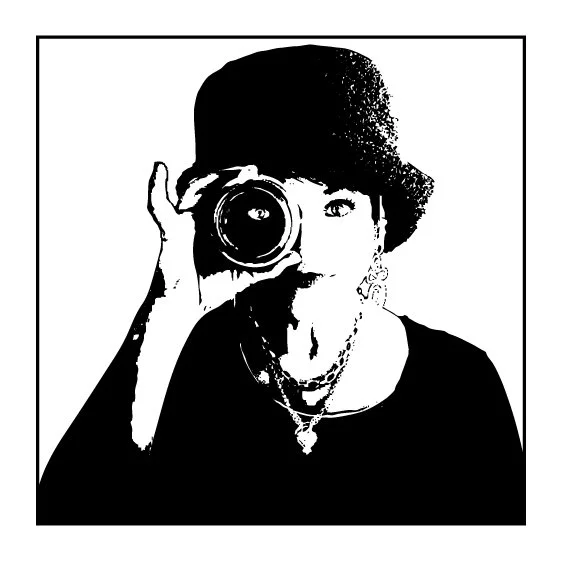 Black and white illustration of photographer Amy Ijams holding a camera lens to her eye, wearing a hat and jewelry.