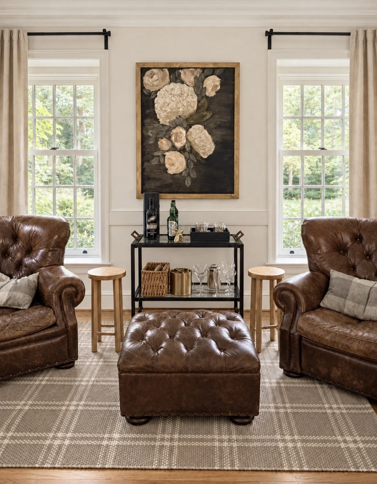 Sitting room with leather wingback chairs, a leather ottoman and floral artwork in a Main Line home