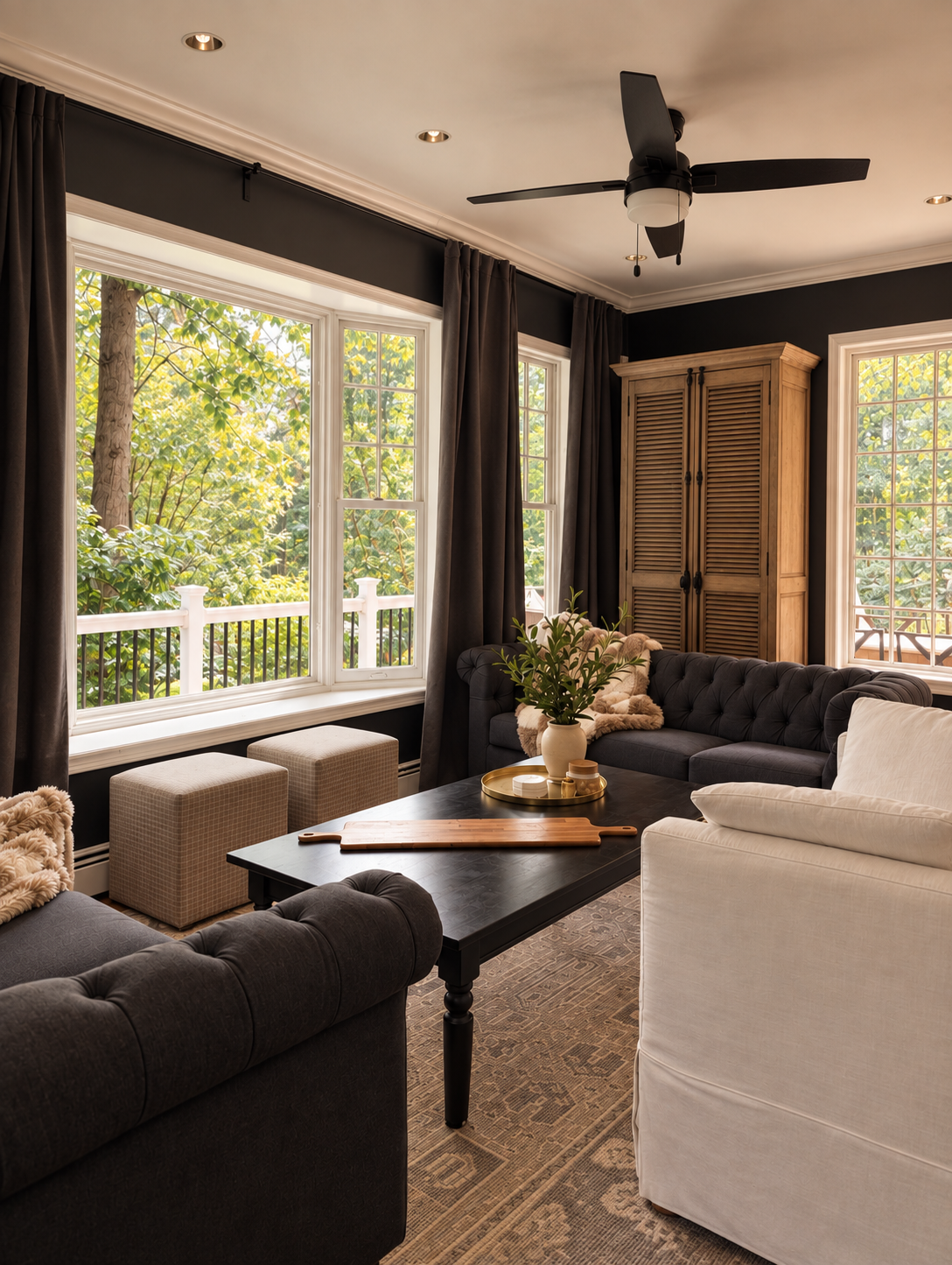 Living room with black walls, a leather Chesterfield sofa and tall windows in a Main Line home