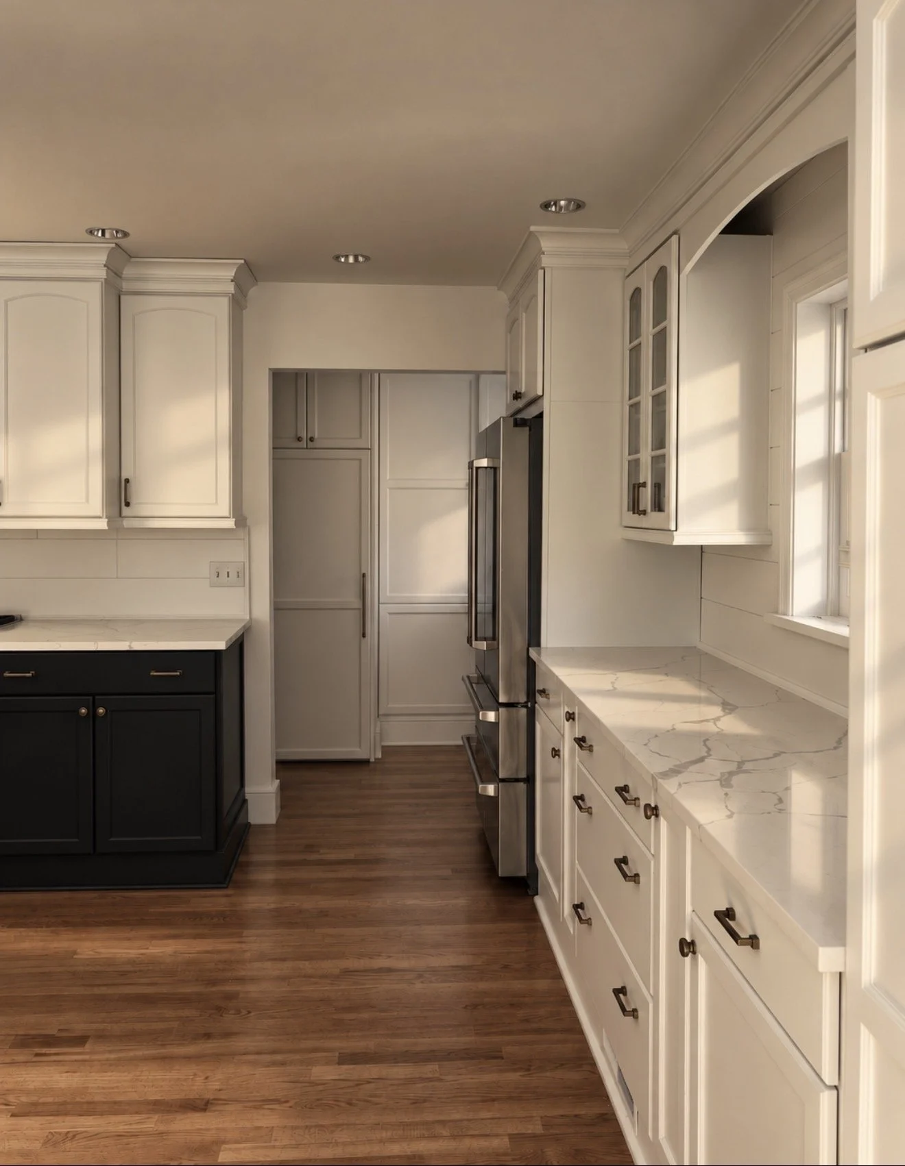 White kitchen with a dark painted island and wood floors in a Main Line home