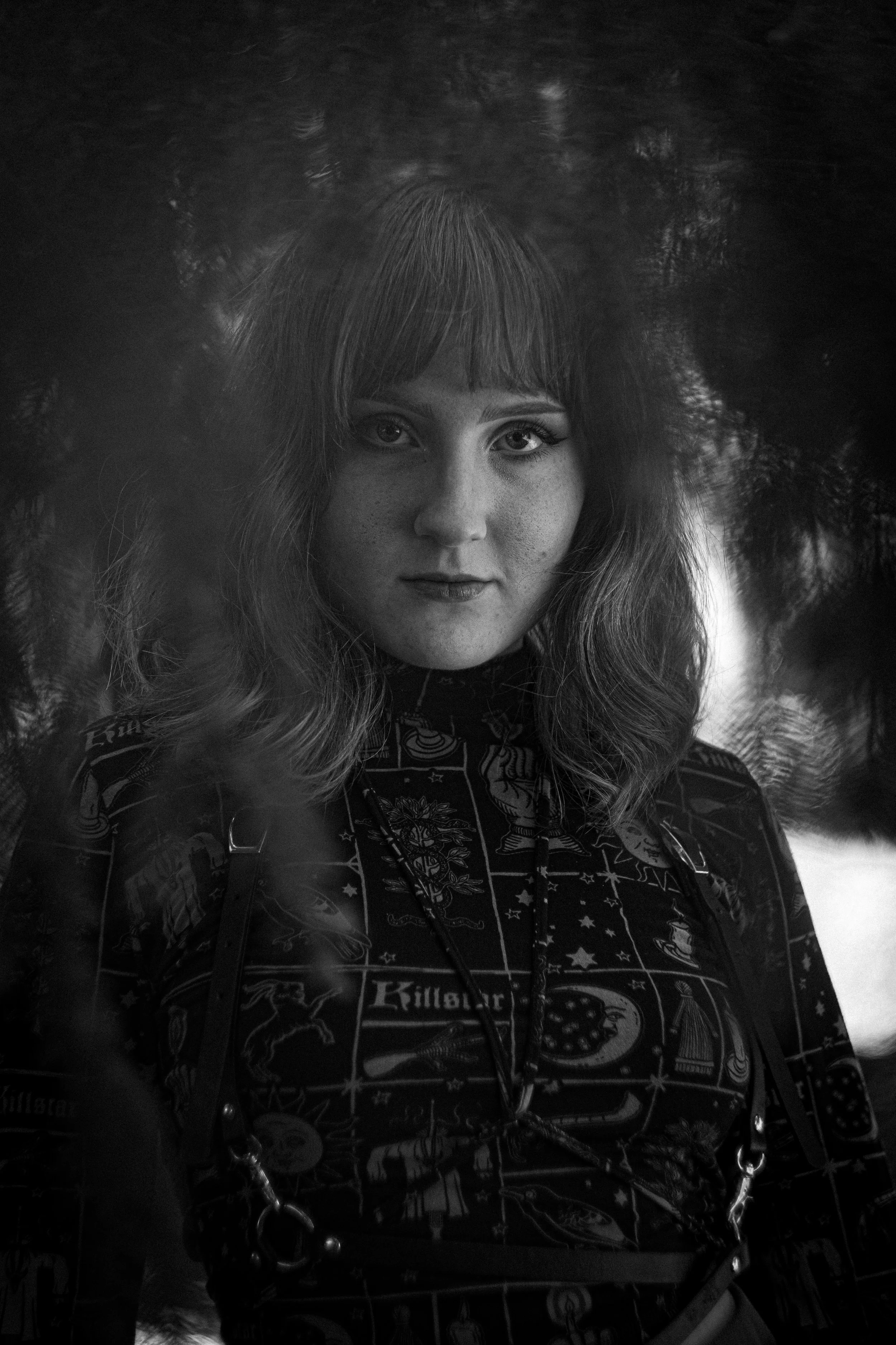 Schwarz-weiß-Foto eines Mädchens mit langen Haaren und dunklen Augen, das in die Kamera schaut, mit einem Muster auf ihrer Kleidung.
