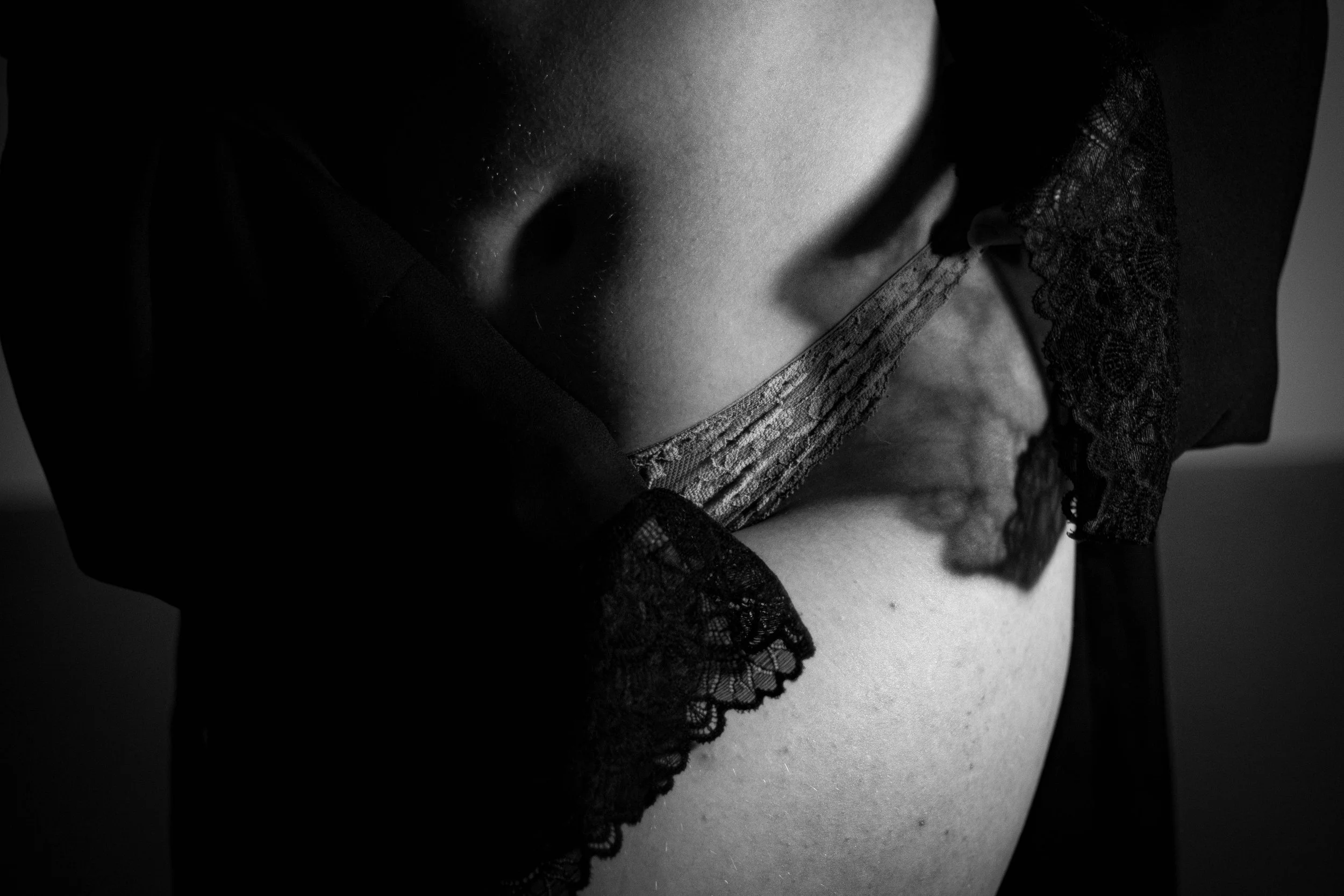 Schwarzes und weißes Bild einer Person mit Lace-Detail an der Unterwäsche, Nahaufnahme am Körper.