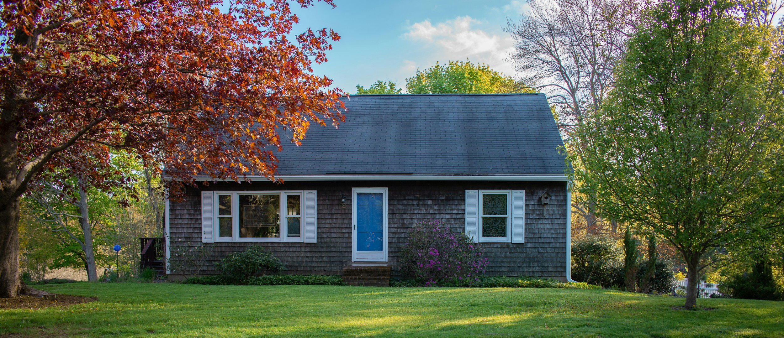 Gray shingle New Hampshire home with white-trimmed windows and green lawn