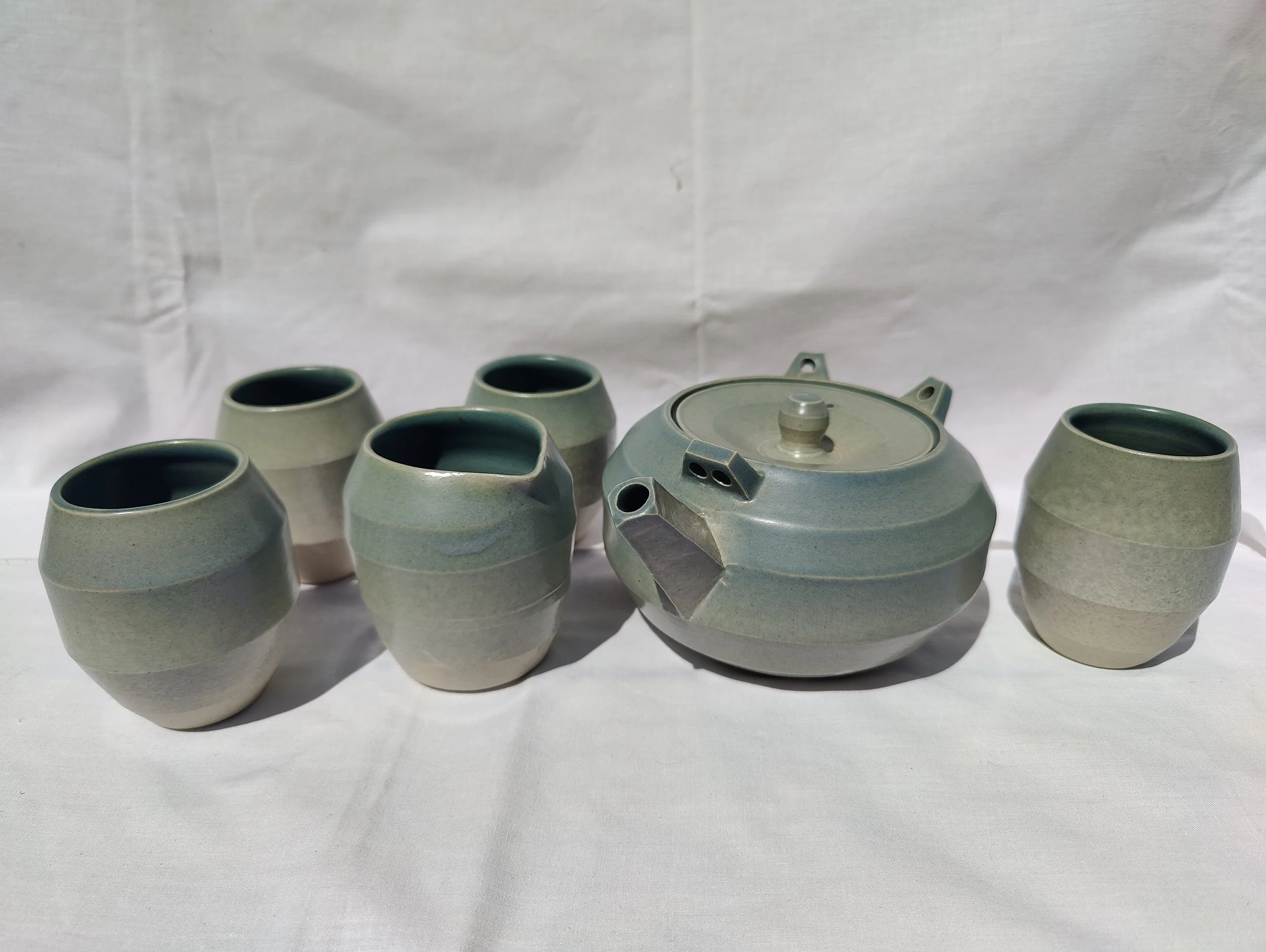Joc de te artesanal de gres blanc de la Bisbal, amb tetera, quatre gots i gerra de llet esmaltats en verd celadó, fet a mà al torn per Ceràmiques PasVi.