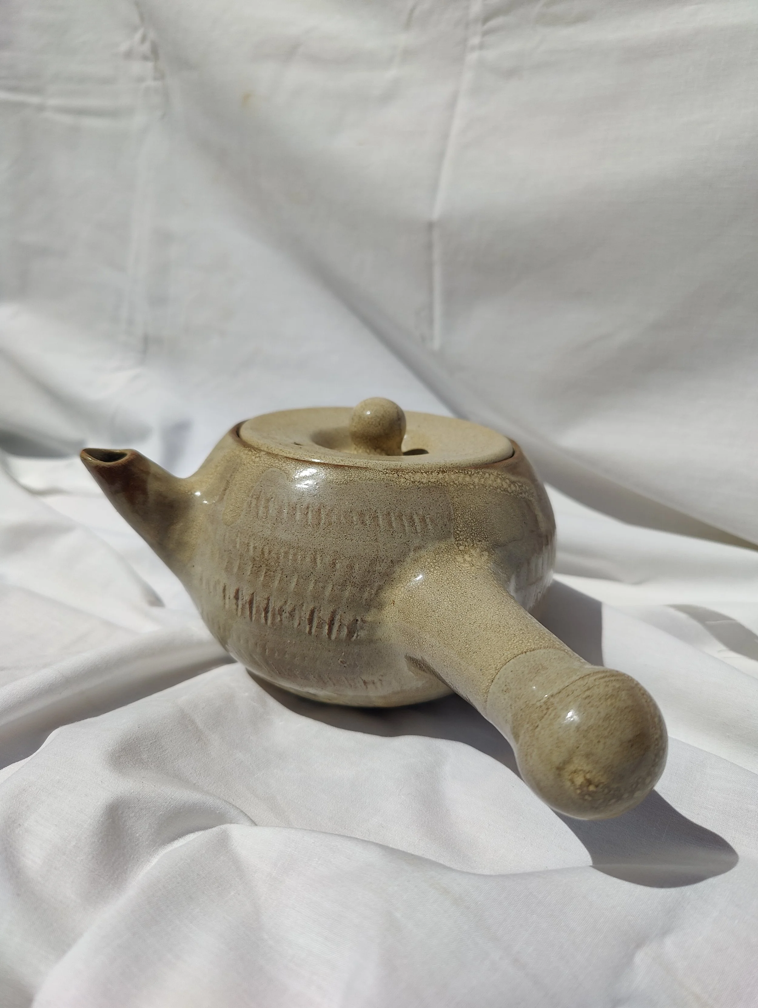 Tetera artesanal de nansa lateral estil kyusu, modelada al torn amb argila vermella de La Bisbal d'Empordà per Ceràmiques PasVi.