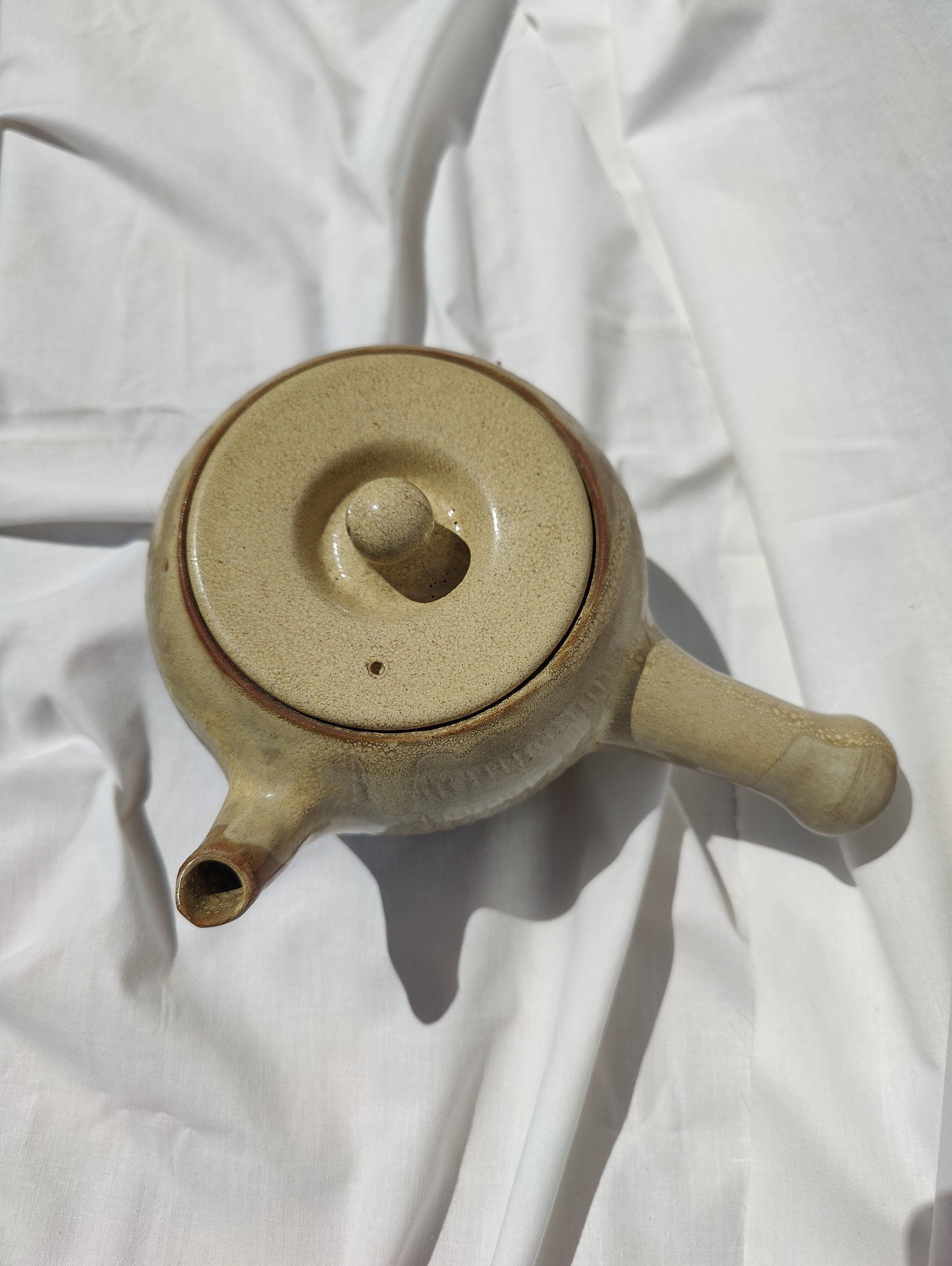 Tetera artesanal de nansa lateral estil kyusu, modelada al torn amb argila vermella de La Bisbal d'Empordà per Ceràmiques PasVi.