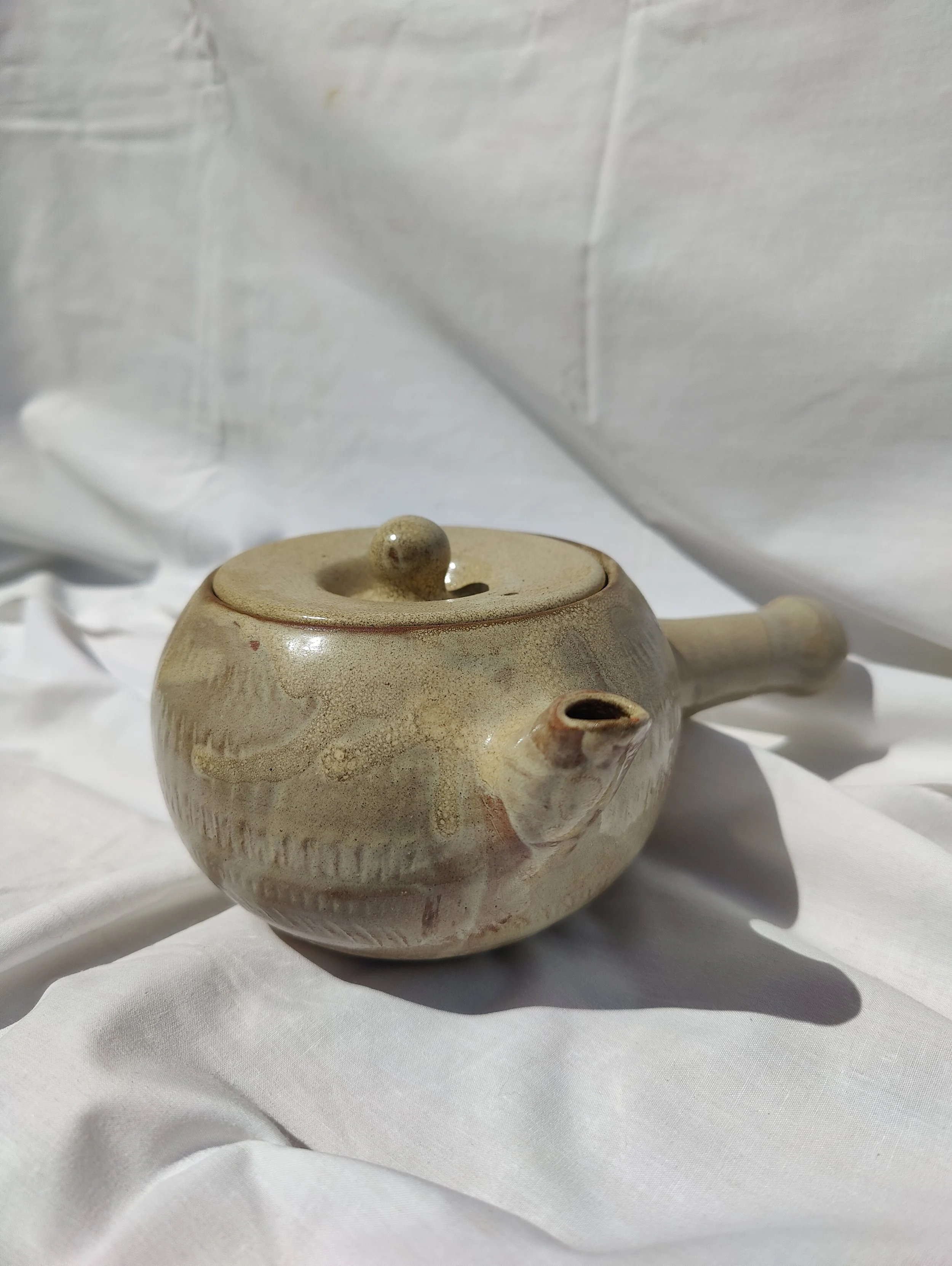 Tetera artesanal de nansa lateral estil kyusu, modelada al torn amb argila vermella de La Bisbal d'Empordà per Ceràmiques PasVi.