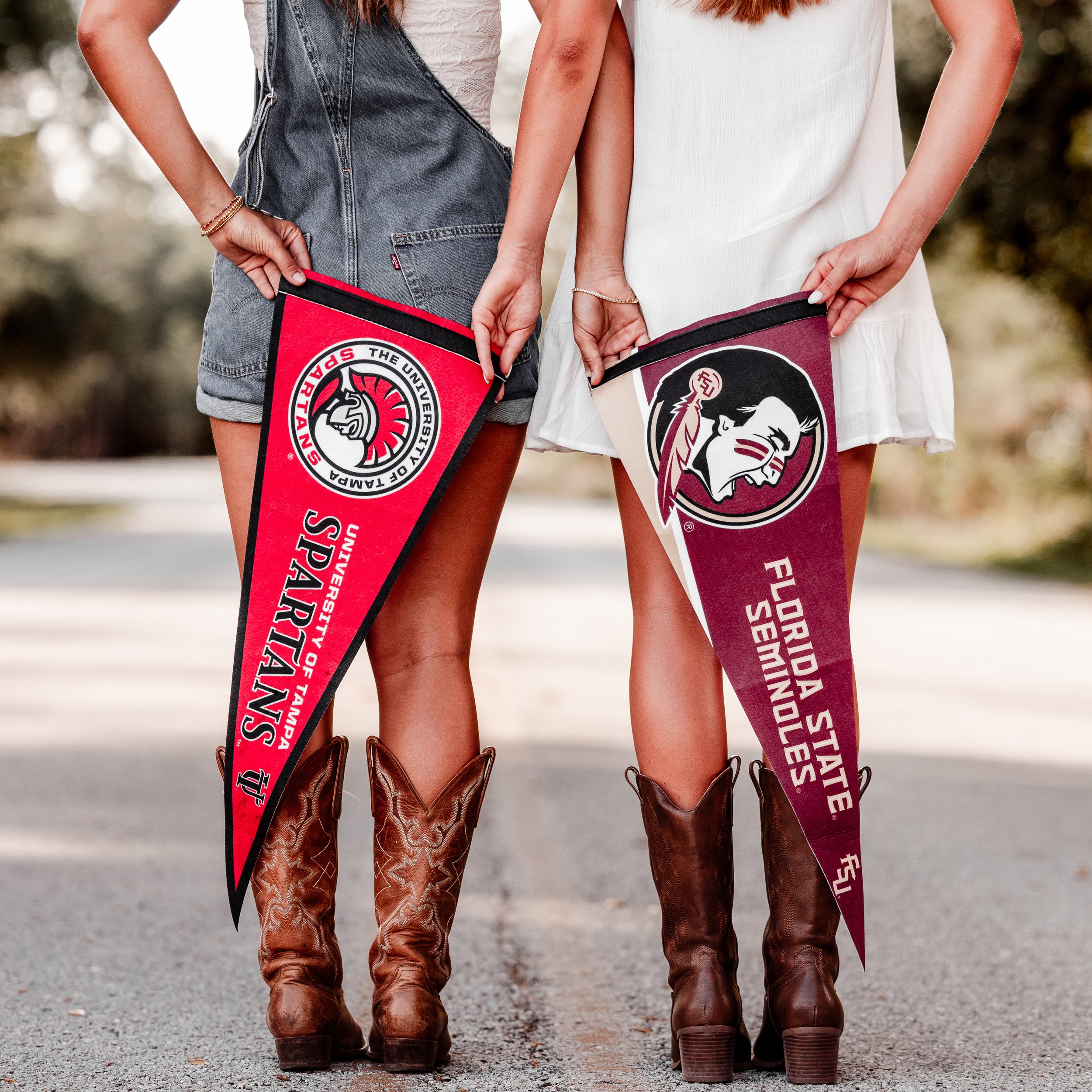 Two women wearing cowboy boots and dresses holding flags of the Texas State University and Florida State University