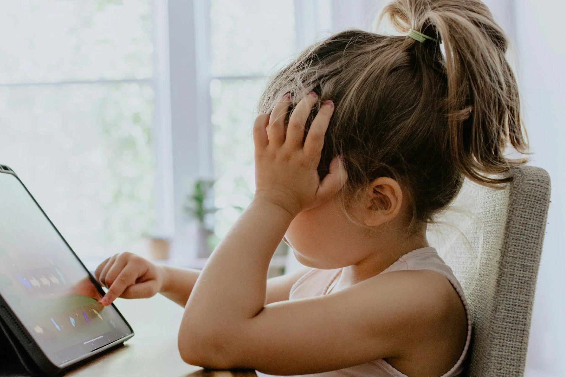 A 4-year old girl whose nervous system is struggling to regulate while she scrolls through her tablet.