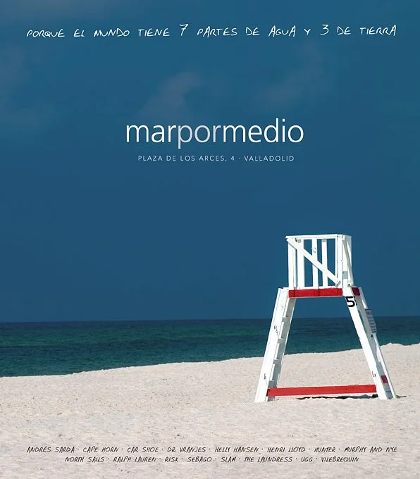 Cartel con texto promocional sobre el Mar Mediterráneo, mostrando una playa con arena y el océano, y una boya en la arena.