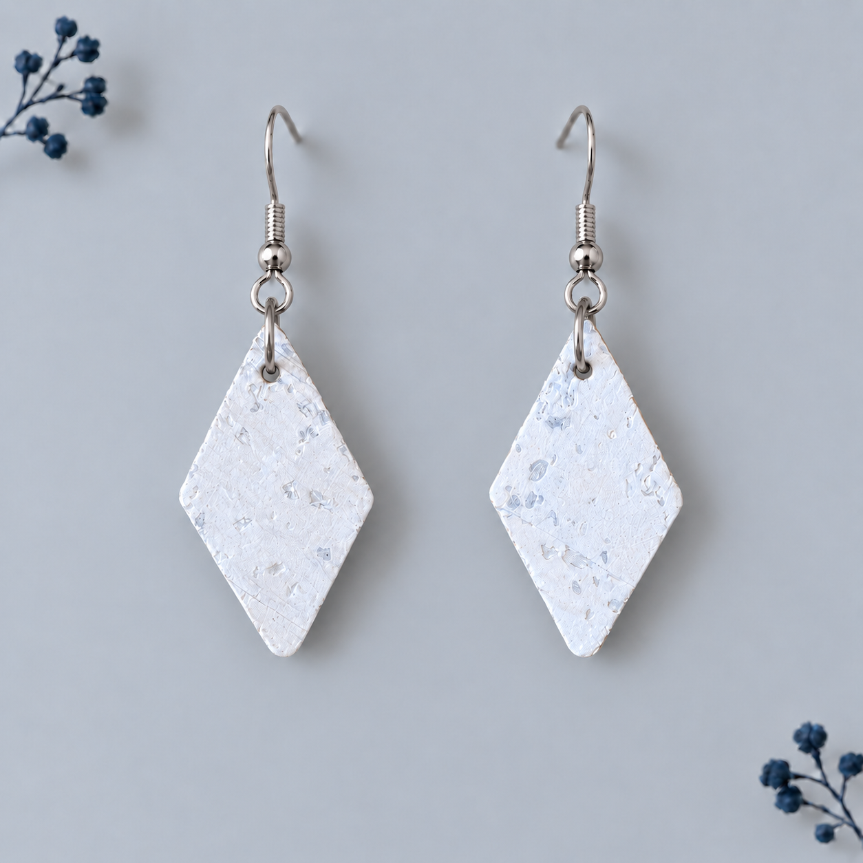 Earrings with diamond shaped white  cork fabric and silver colored hooks.