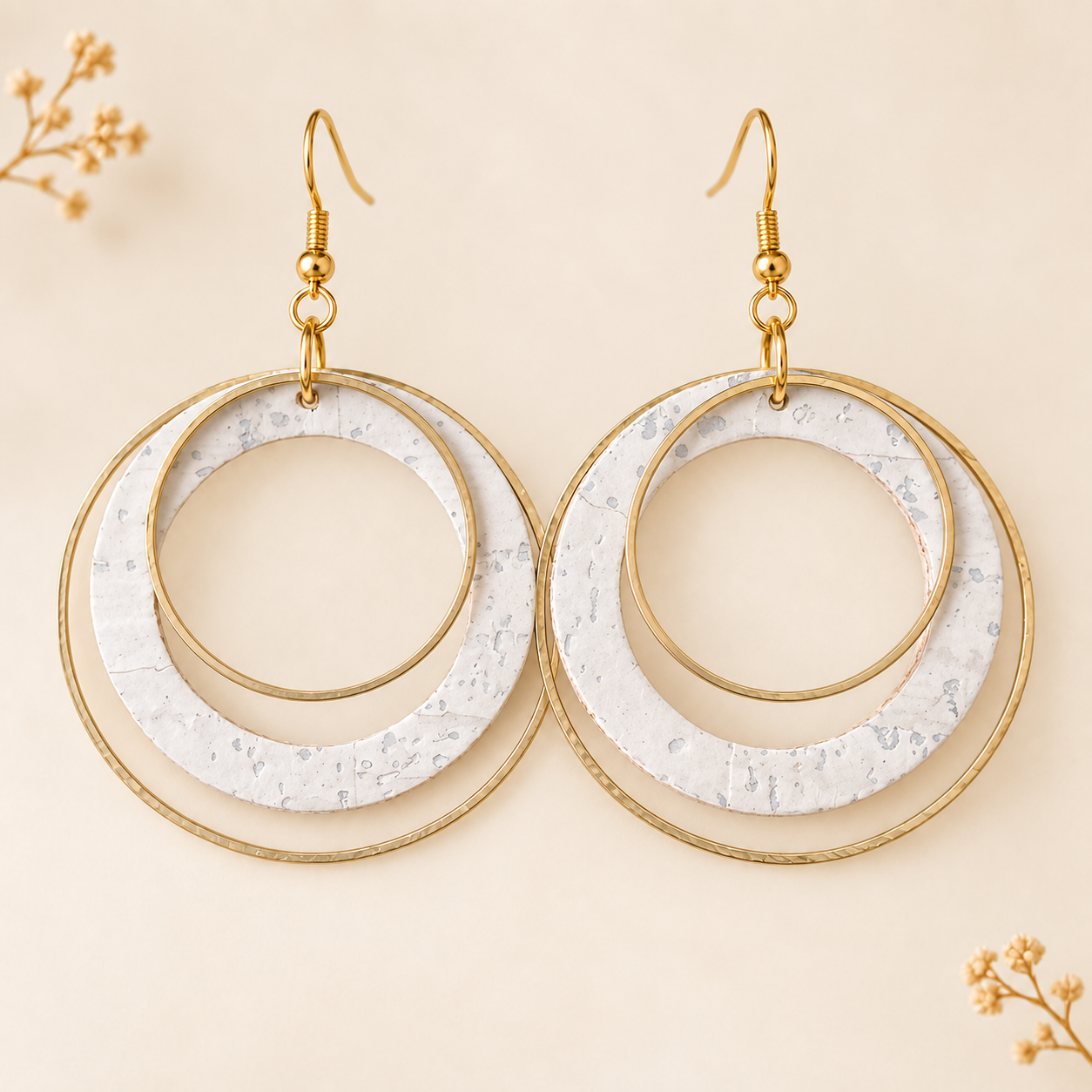 White cork fabric earrings with overlapping gold color hoops.