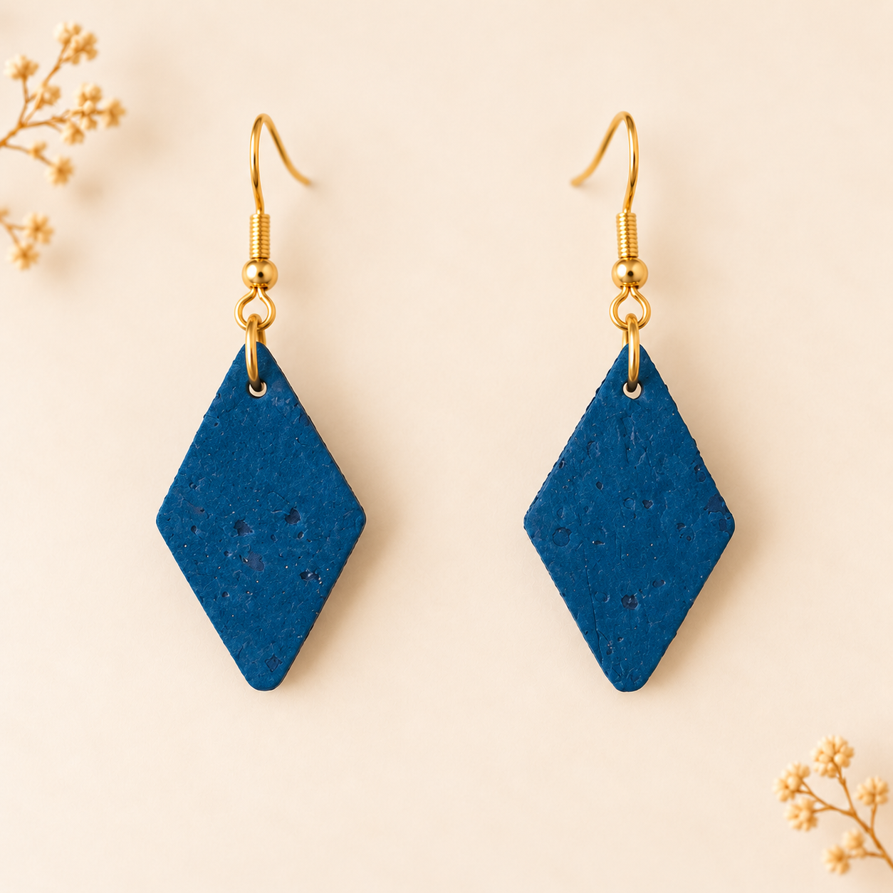 Earrings with diamond shaped teal colored cork fabric and gold colored hooks.