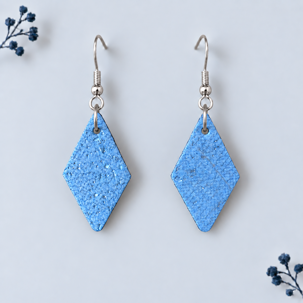 Earrings with diamond shaped metallic blue colored cork fabric and silver colored hooks.