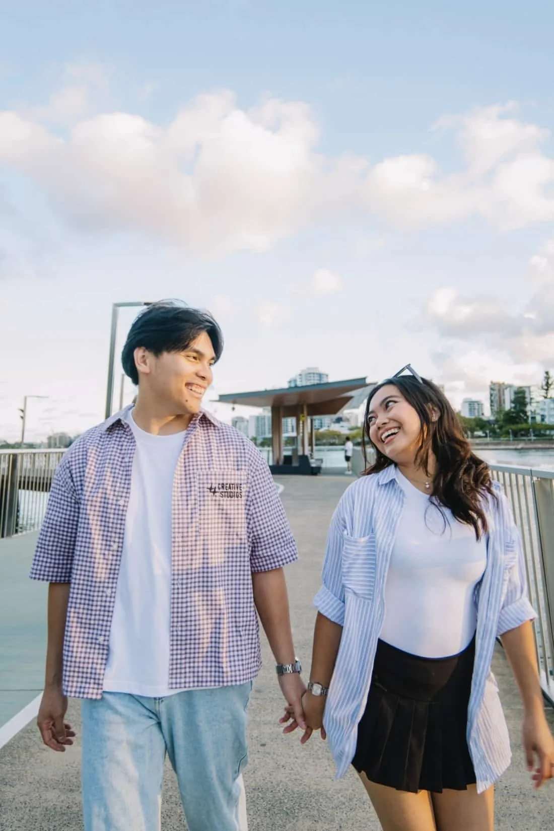Couple walking hand in hand with a sunny city skyline behind them