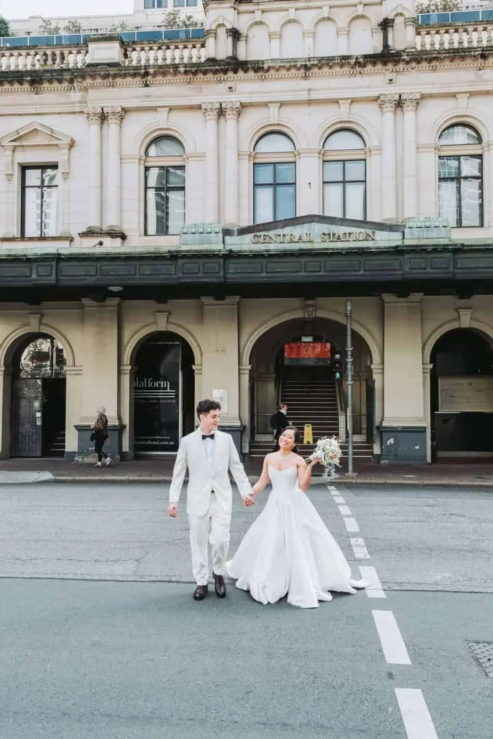 Newlyweds walking past a historic Brisbane building after their ceremony