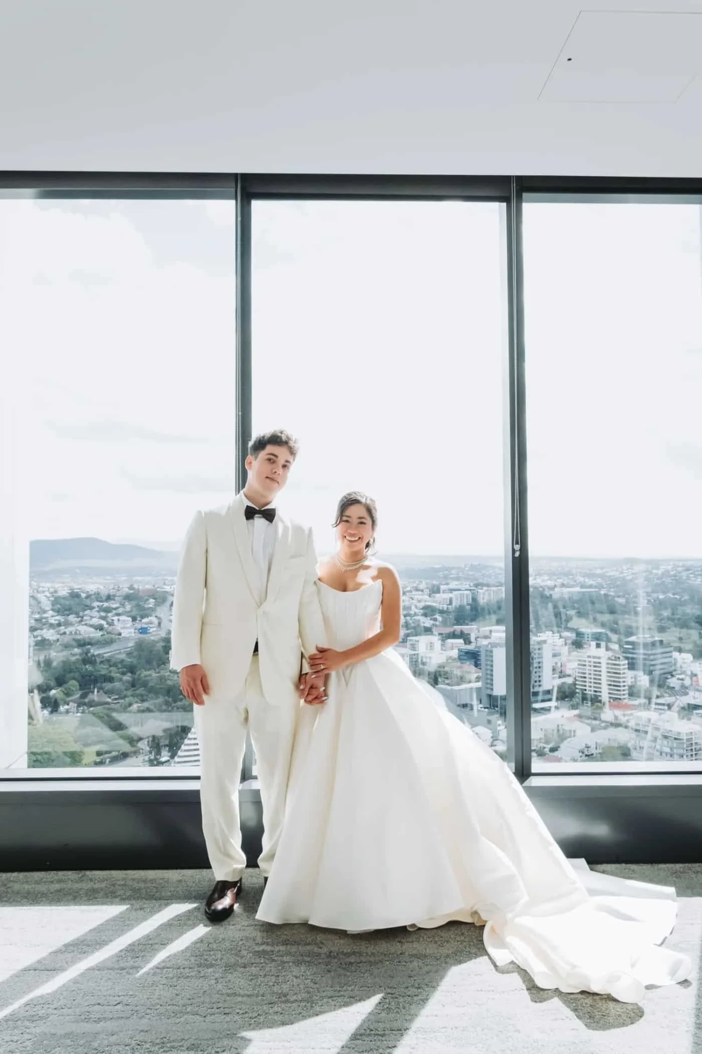 Bride in a white gown with bridesmaids in a sunlit city venue