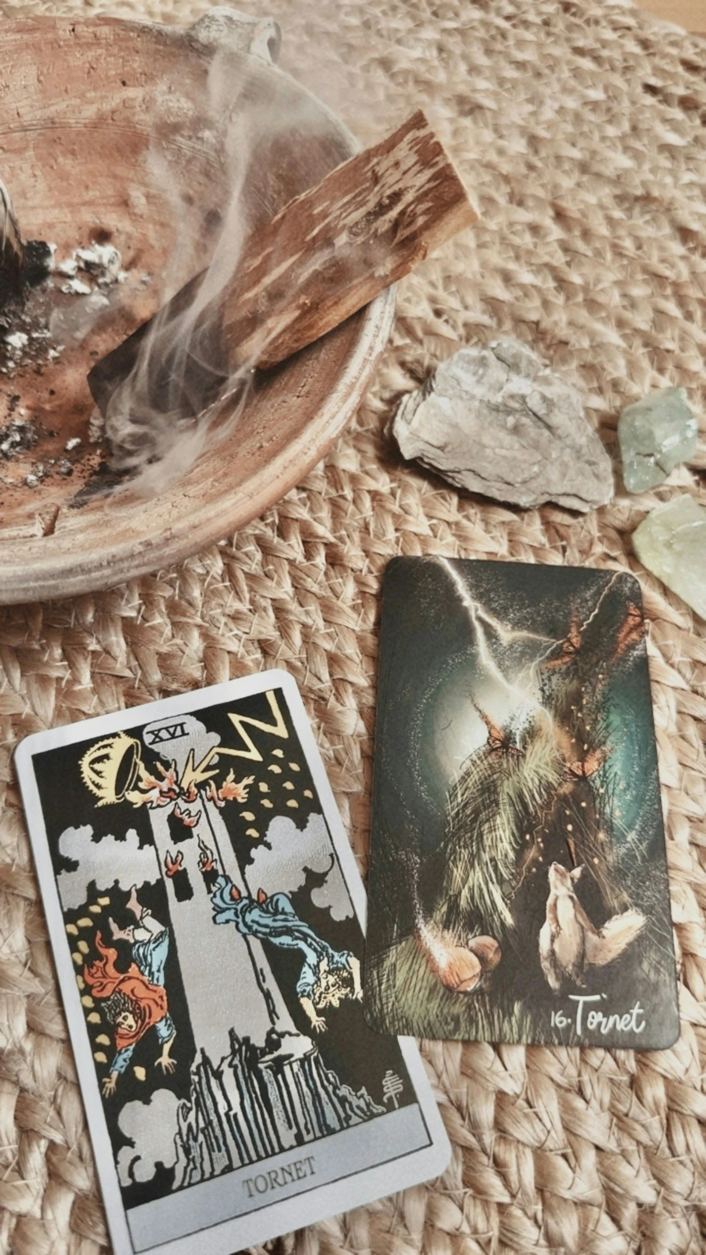A Tarot card named 'Tornet' depicting a scene with lightning and a wolf, a crystal, a stone, a wooden bowl with burning incense, and another card in the background.