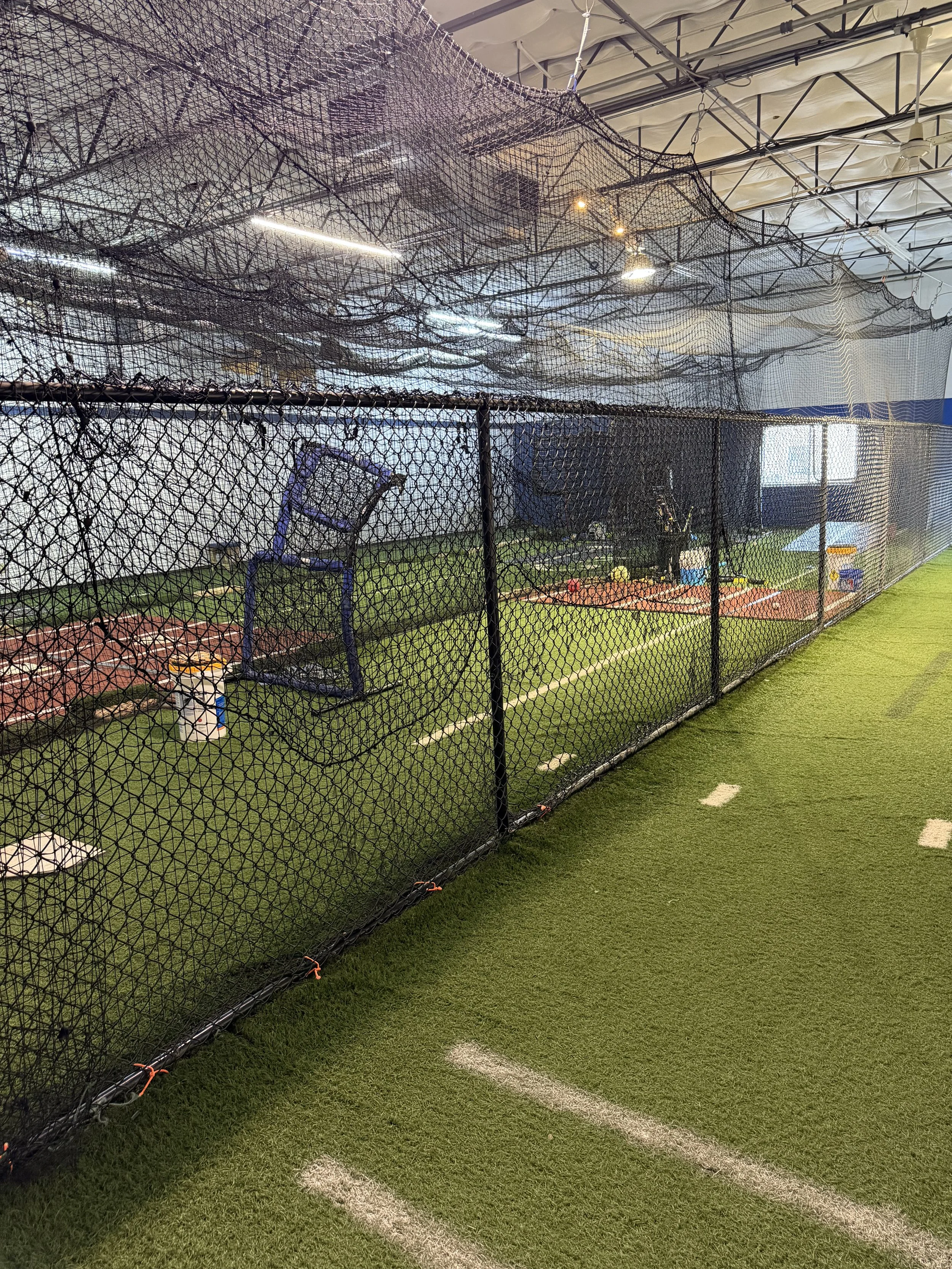 Indoor sports practice area in Southlake Texas with batting cage, nets, and artificial turf.