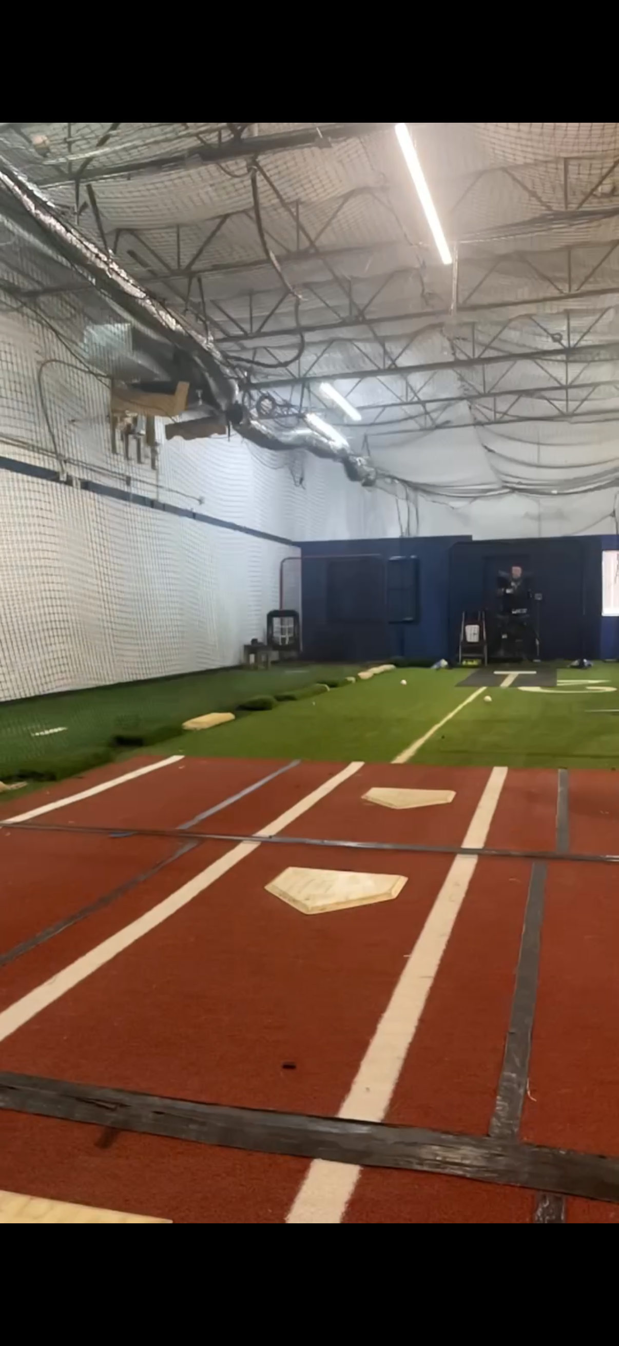 Indoor sports training facility with batting cages, turf, and batting mats for baseball or softball practice.