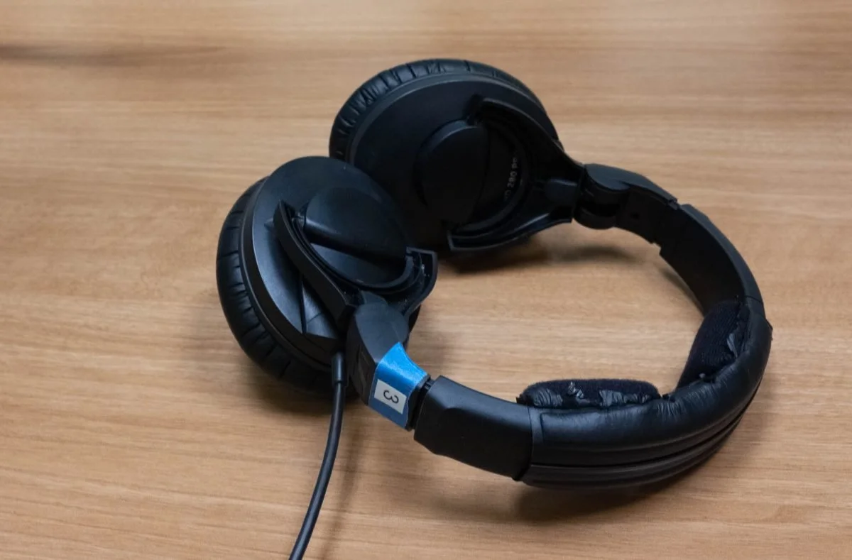 Black over-ear headphones with a coiled cord on a wooden surface.