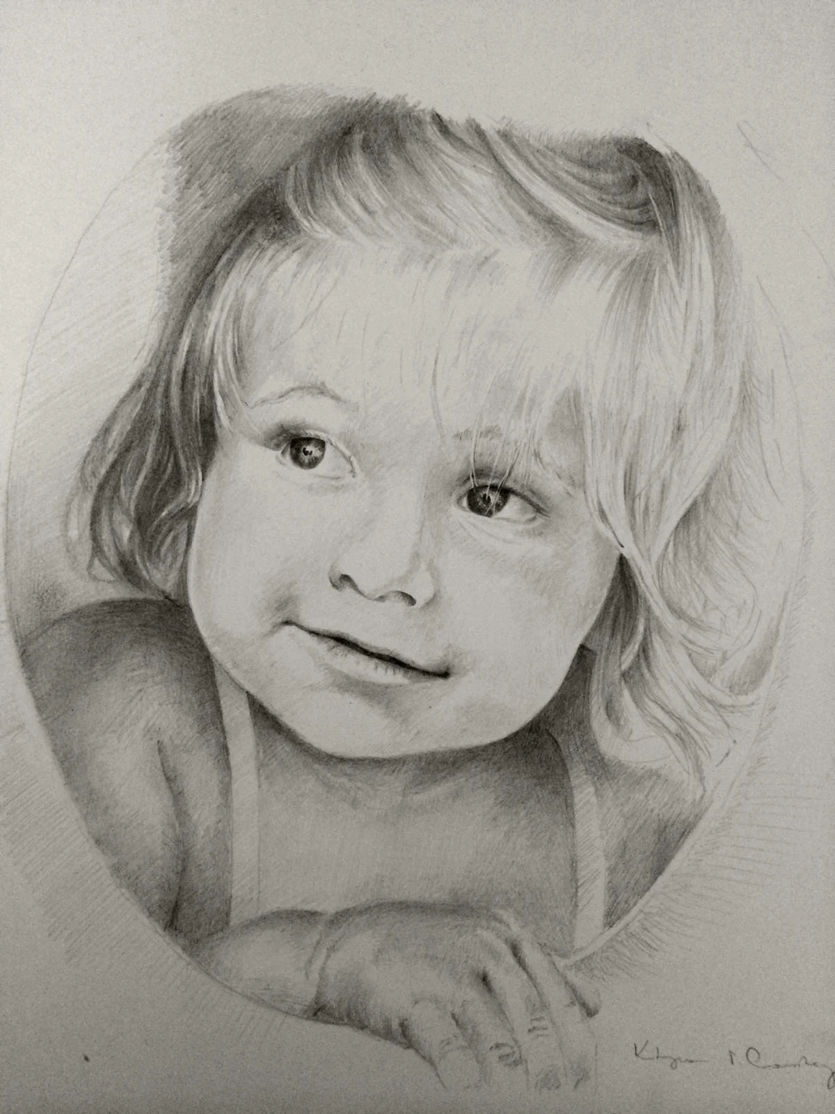 A realistic pencil sketch of a young girl with shoulder-length hair, smiling and lying on her stomach with her head resting on her arms.