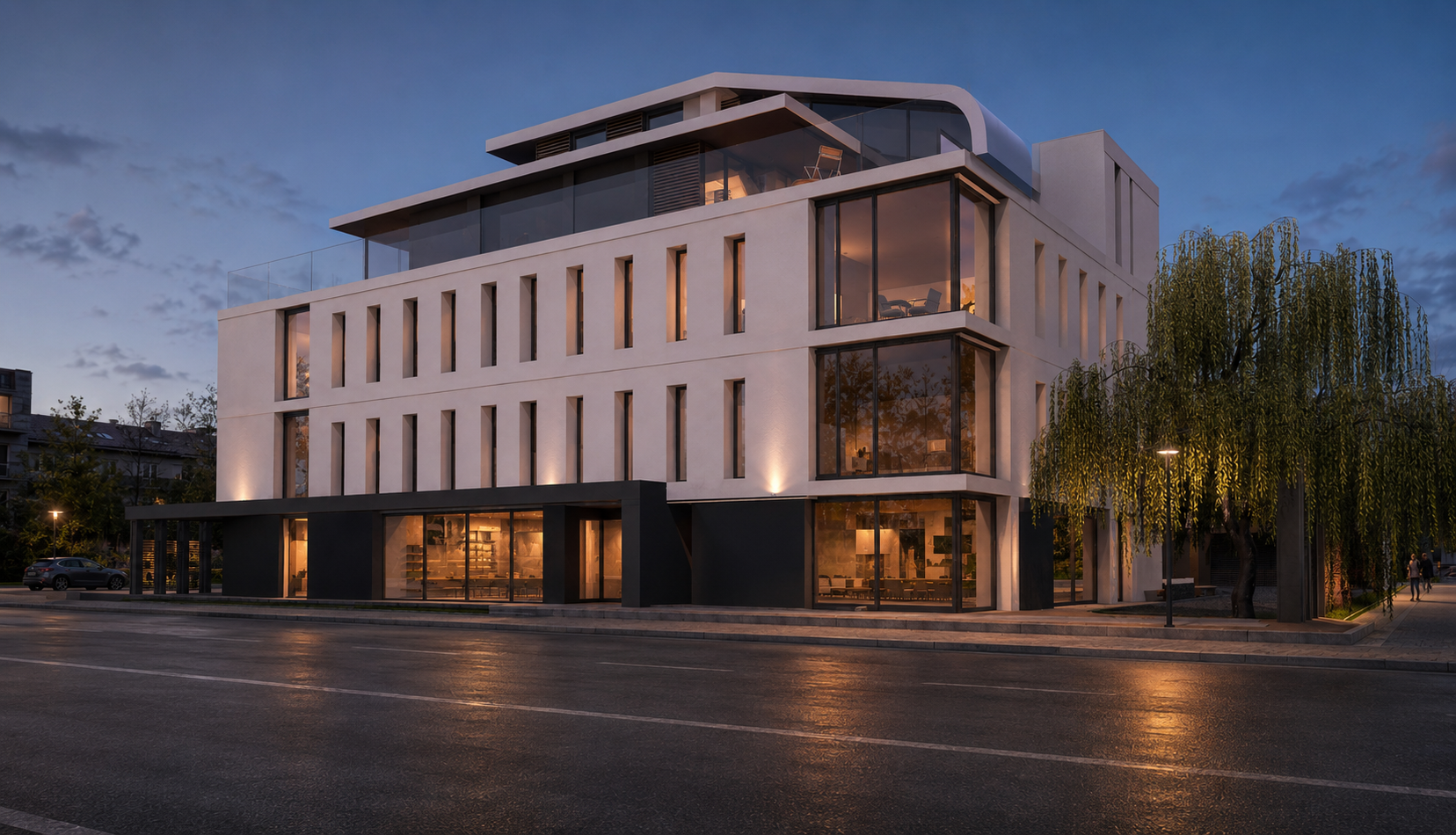Modern multi-story building with large glass windows illuminated at dusk, street in foreground, trees and streetlights nearby.