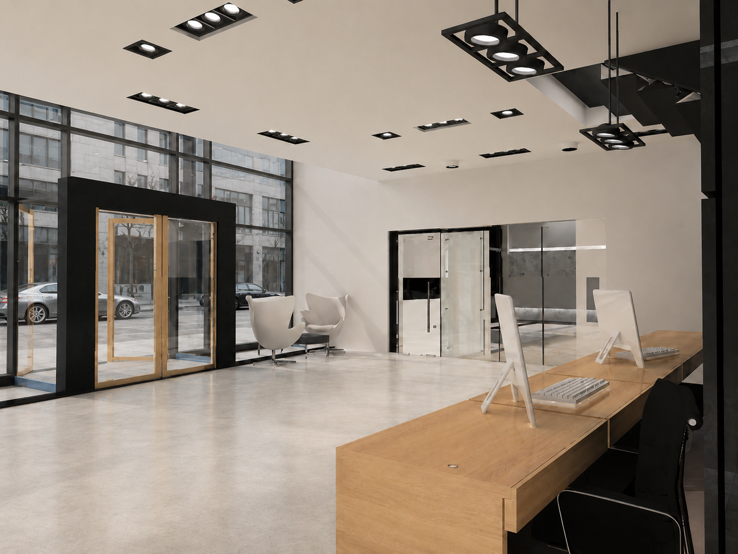 Modern office lobby with large glass windows, white walls, and minimalist furniture, including two white chairs near the window, a wooden reception desk with two desktop computers, and overhead lighting fixtures.