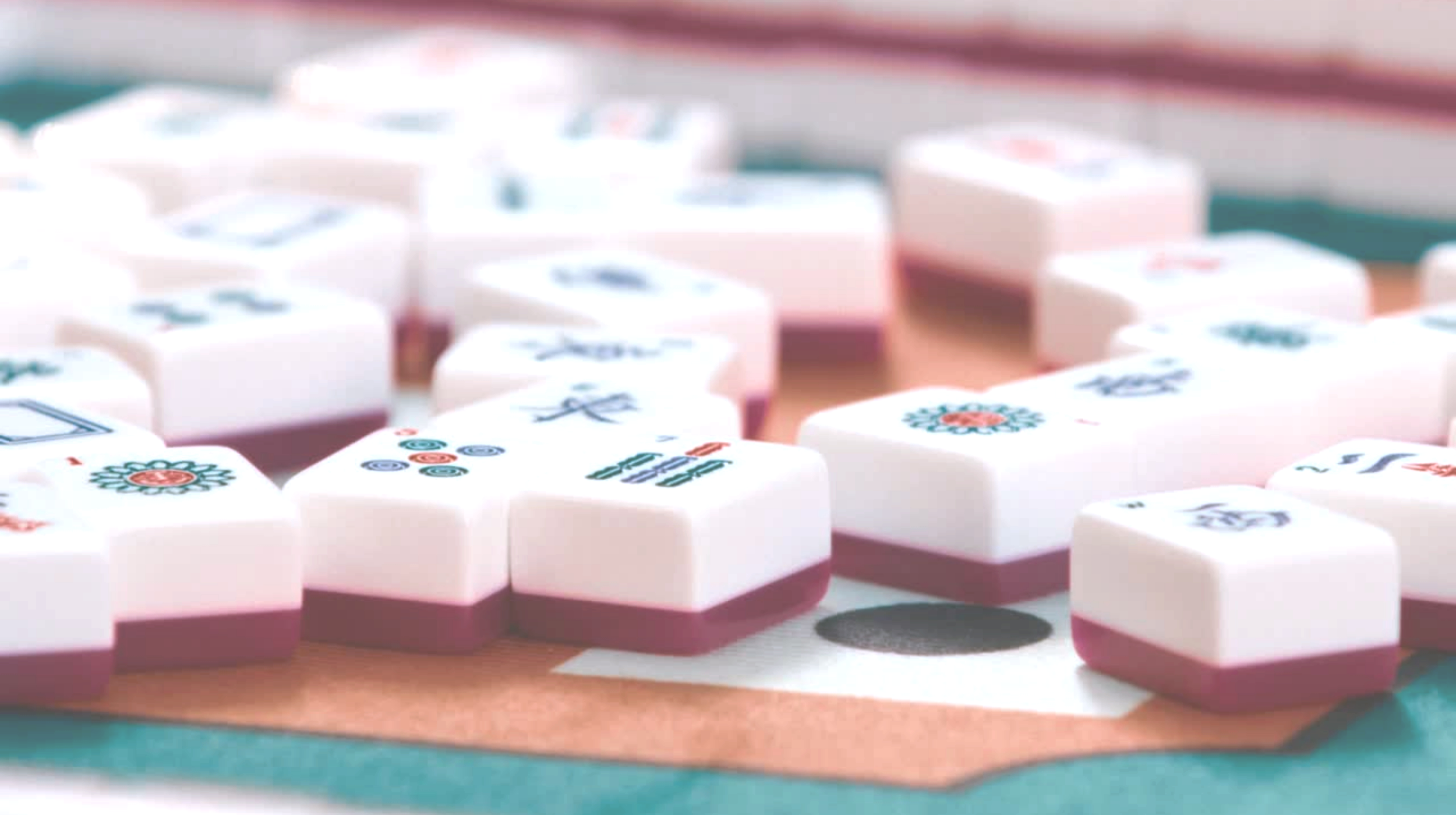 Close-up of mahjong tiles on a game table, some tiles display traditional Chinese characters and symbols.