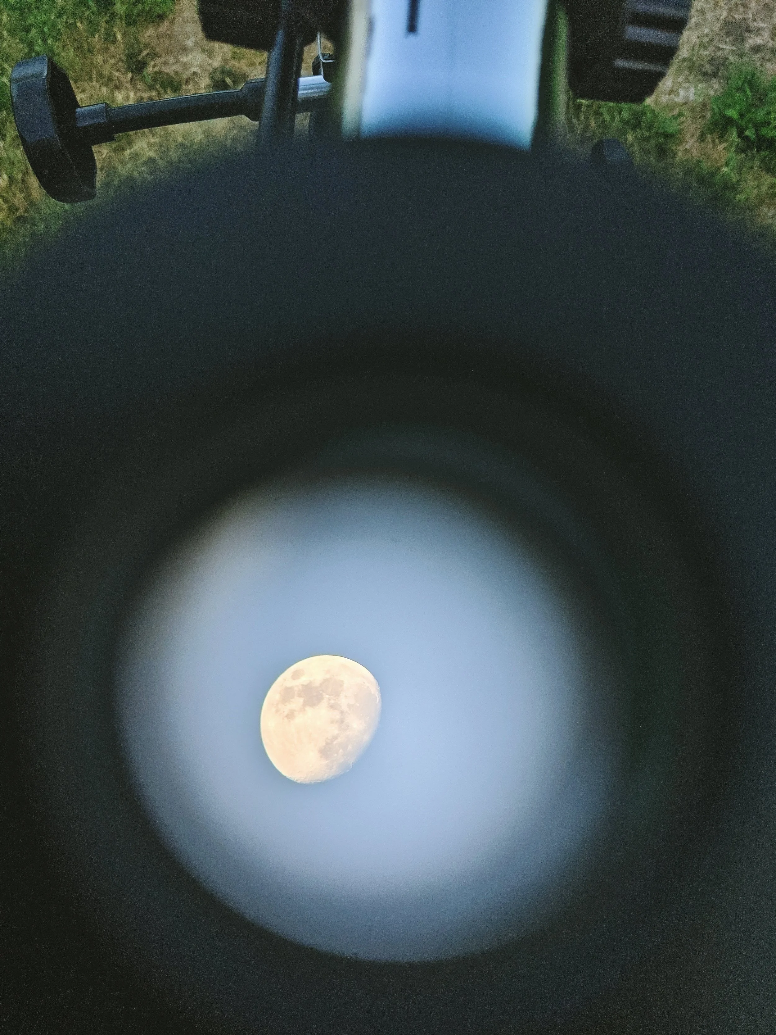 Une photo de la lune visible à travers un télescope, avec des détails de la surface lunaire. La photo est prise de nuit, en extérieur.
