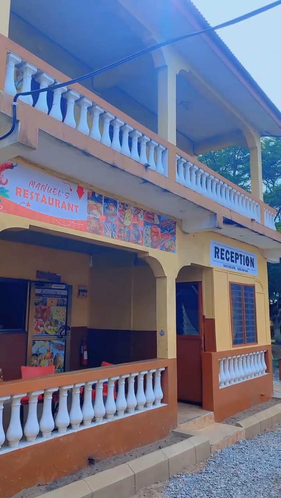 Exterior view of Manuel's Restaurant with a reception area, balcony, and colorful sign.
