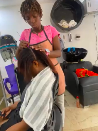 A young girl getting her hair styled in a salon with a stylist working on her hair.