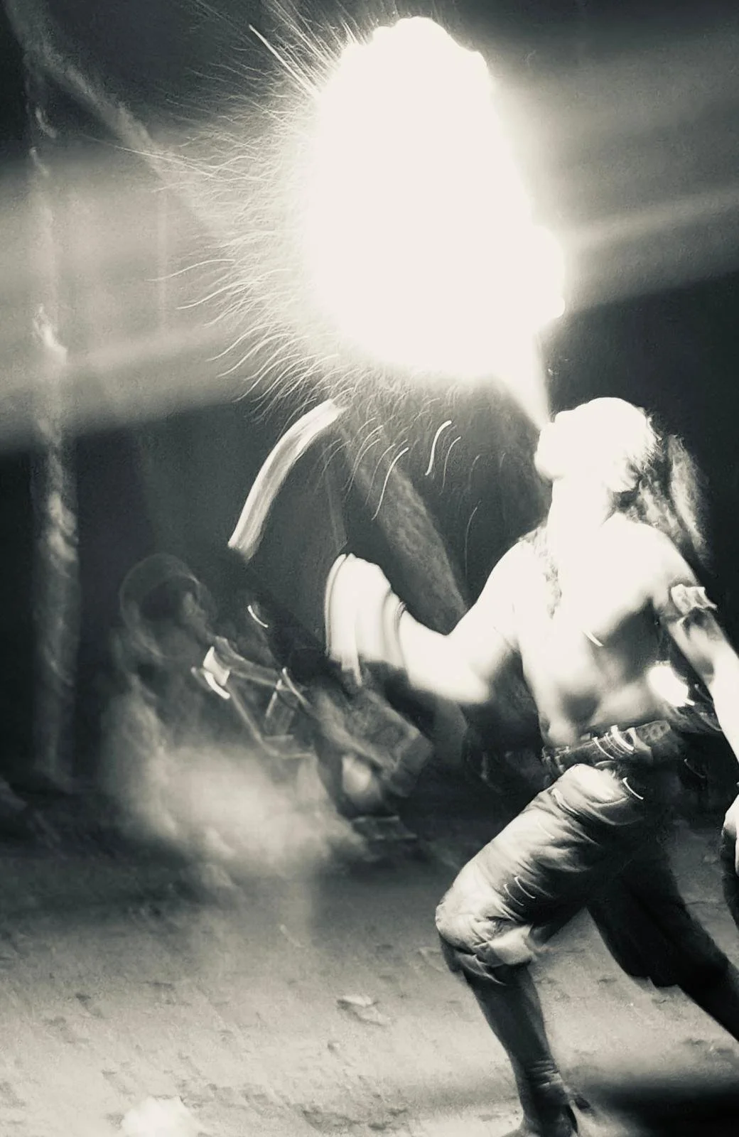 A black and white photo of a man spitting a large plume of fire from his mouth.