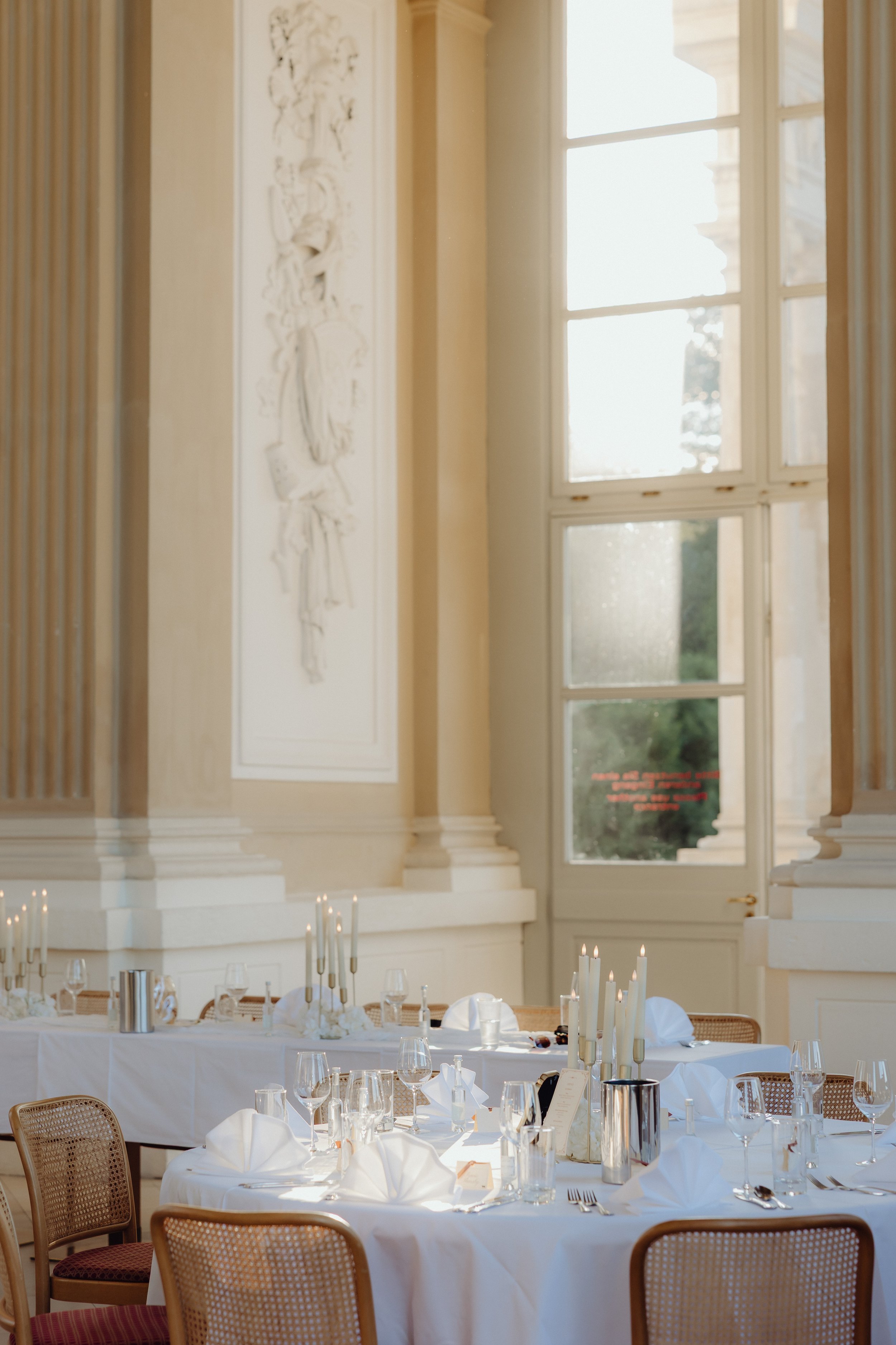 Elegant wedding reception in a grand historic venue featuring beautifully arranged tables, white linens, candlelit centerpieces, and classic architectural details.