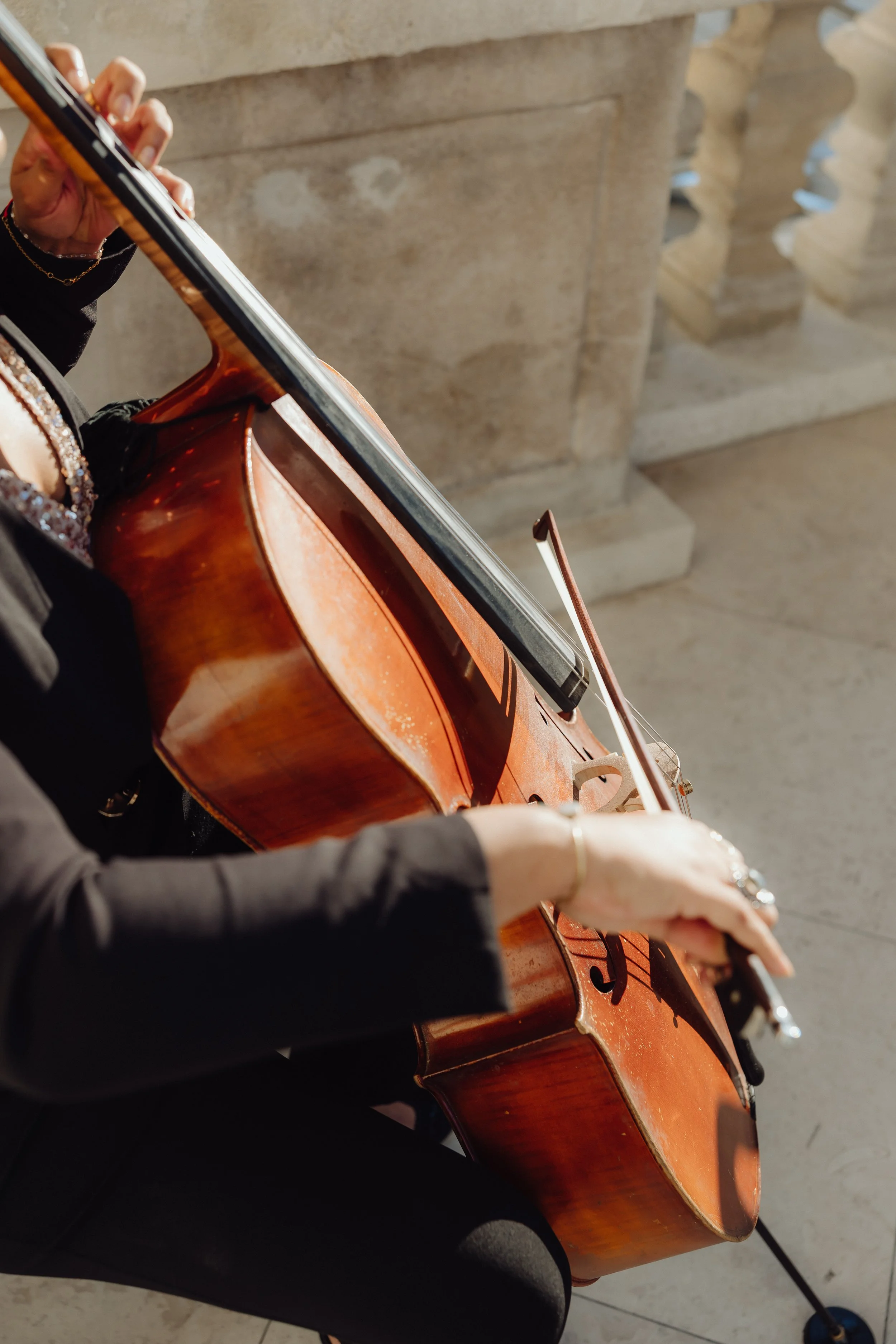 Cellist performing live classical music during an elegant outdoor wedding celebration.