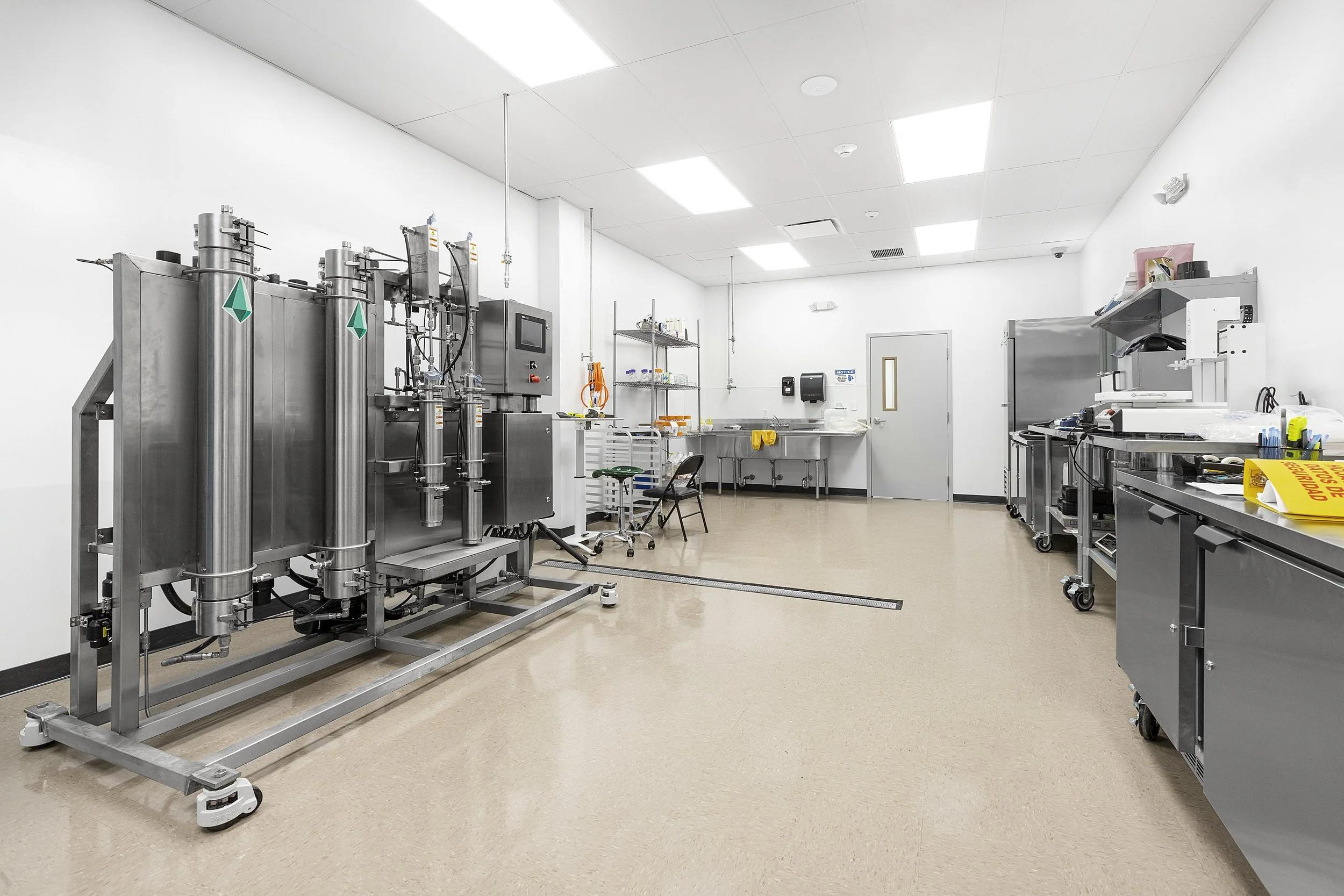 Clean medical or laboratory room with equipment, stainless steel surfaces, and white walls.