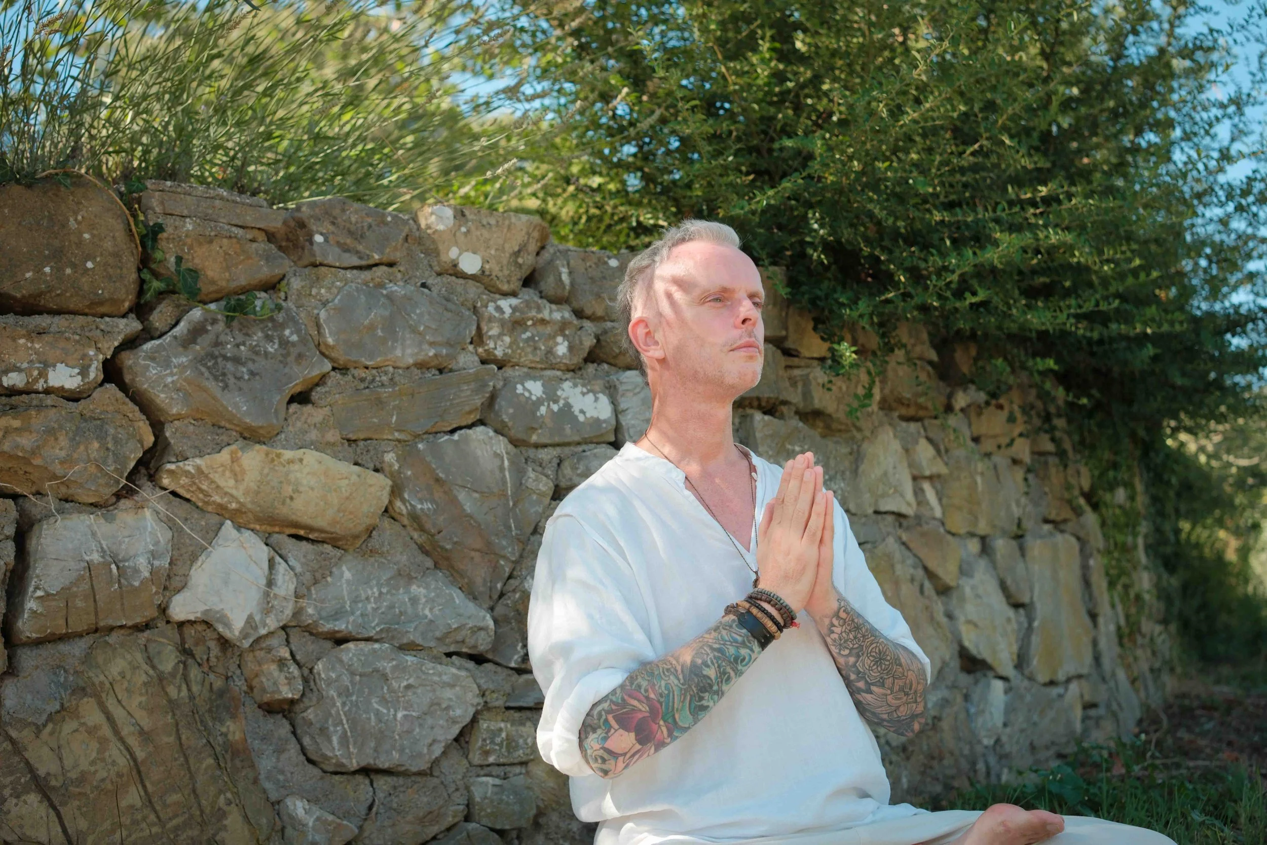 Michael Reiley sitting with his hands crossed in front of a stone wall.