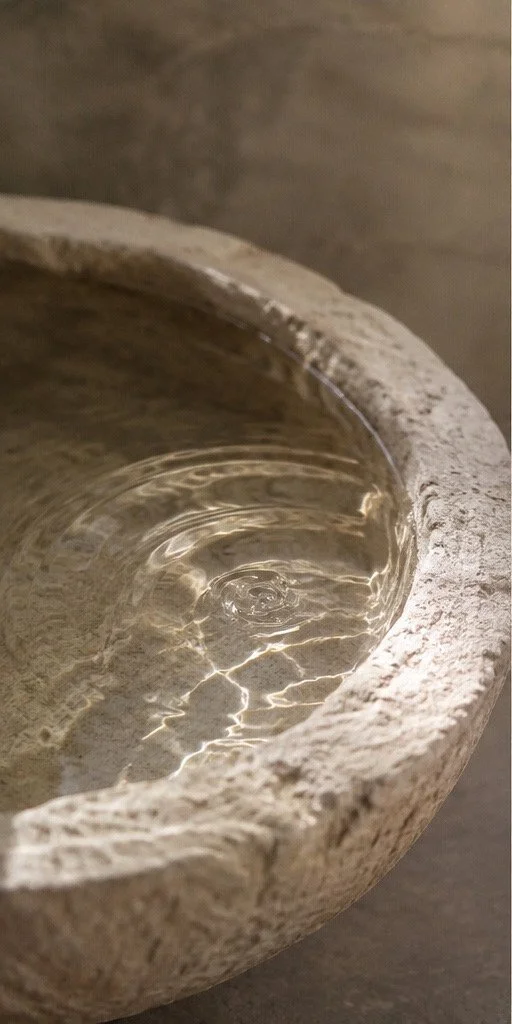 Close-up of empty stone bowl with water and light reflections inside