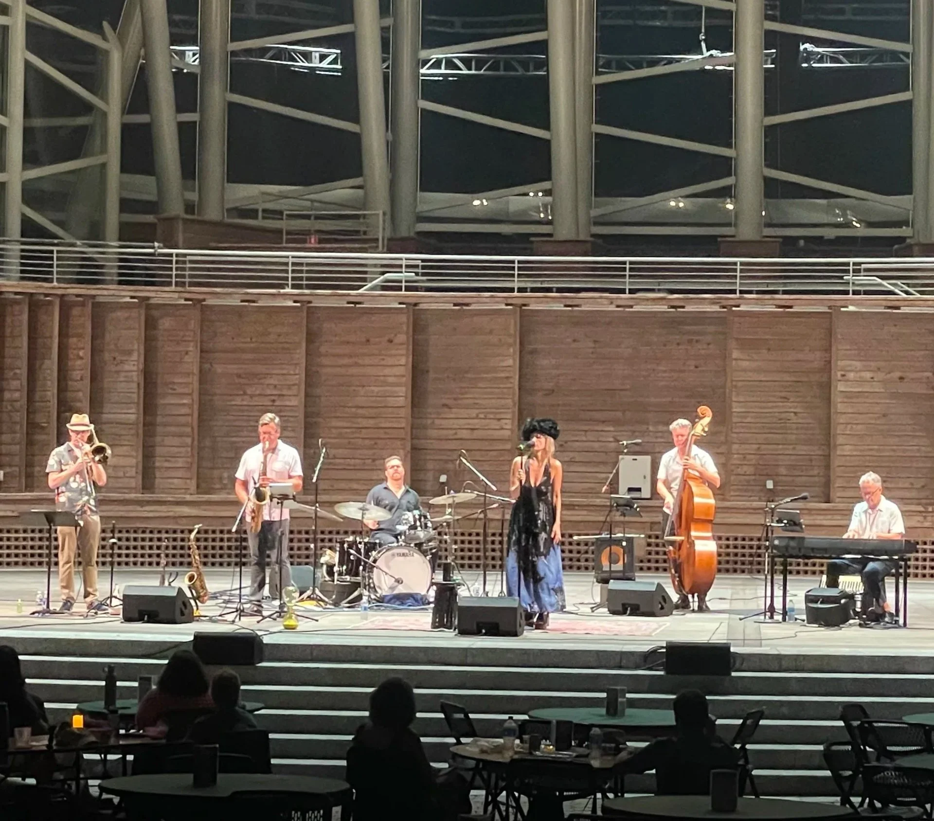 A band of musicians performing on a stage in an outdoor concert space. Koko booth amphitheater in Cary, NC. Daniel Hall is playing Yamaha drums.