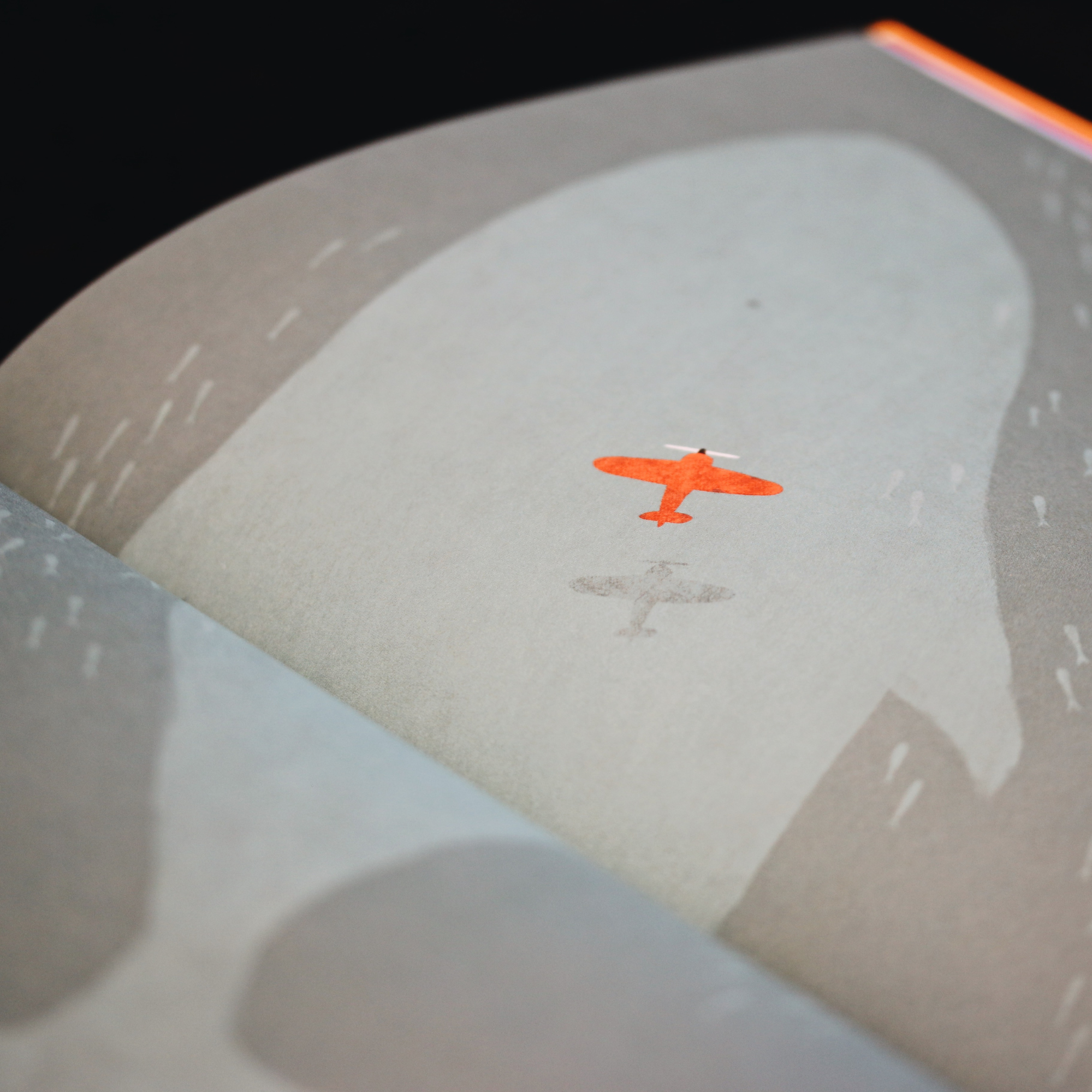 Close-up of an orange helicopter icon on a light gray surface, with part of a circular gray and orange interface element visible.