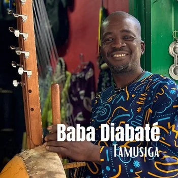 Man smiling and playing a twenty-one stringed traditional Kora, surrounded by textiles and musical instruments in a colorful shop.