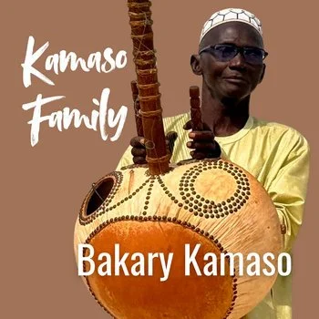 A man wearing glasses and a yellow shirt holding a traditional musical instrument called a kora, a twenty one stringed instrument, with text that reads 'Kamoso Family' and 'Bakary Kamoso' in the background.