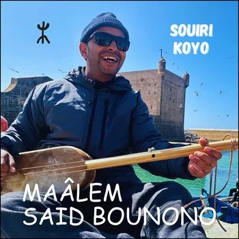 Man wearing sunglasses and a beanie playing a traditional musical instrument, called guembri, outdoors with a historic building in the background, sunny sky, and text overlay reading 'Souri Koyo' and 'Maâlem Said Bounono'.