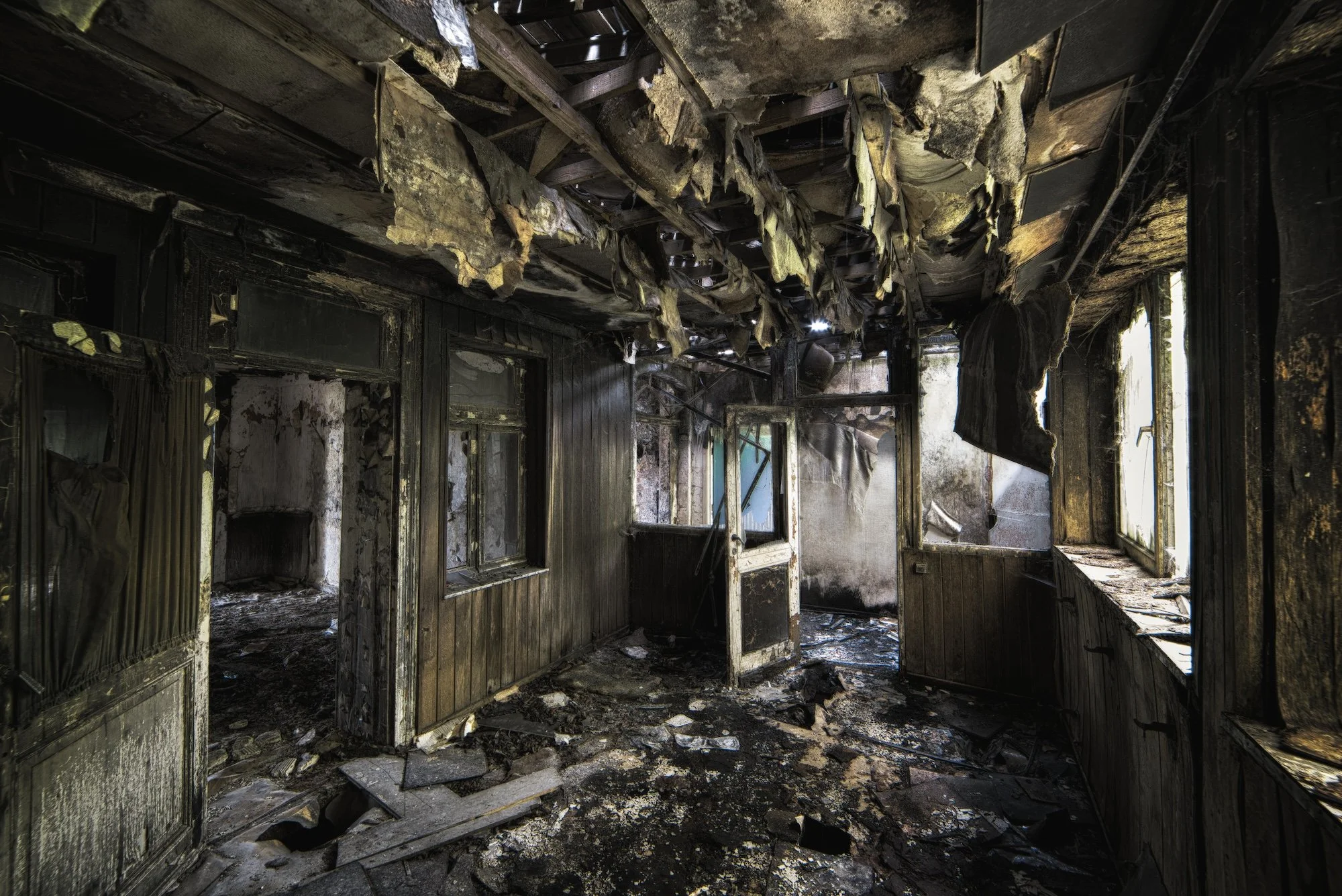 Insurance Adelaide room that has been severely damaged by fire, with the ceiling and walls extensively charred and collapsed, and debris scattered all over the floor.