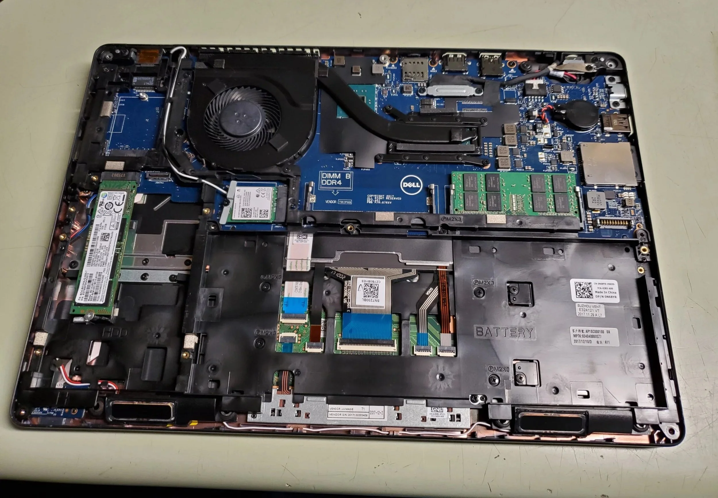 Inside view of a disassembled laptop showing the motherboard, cooling fan, RAM modules, and various internal components.