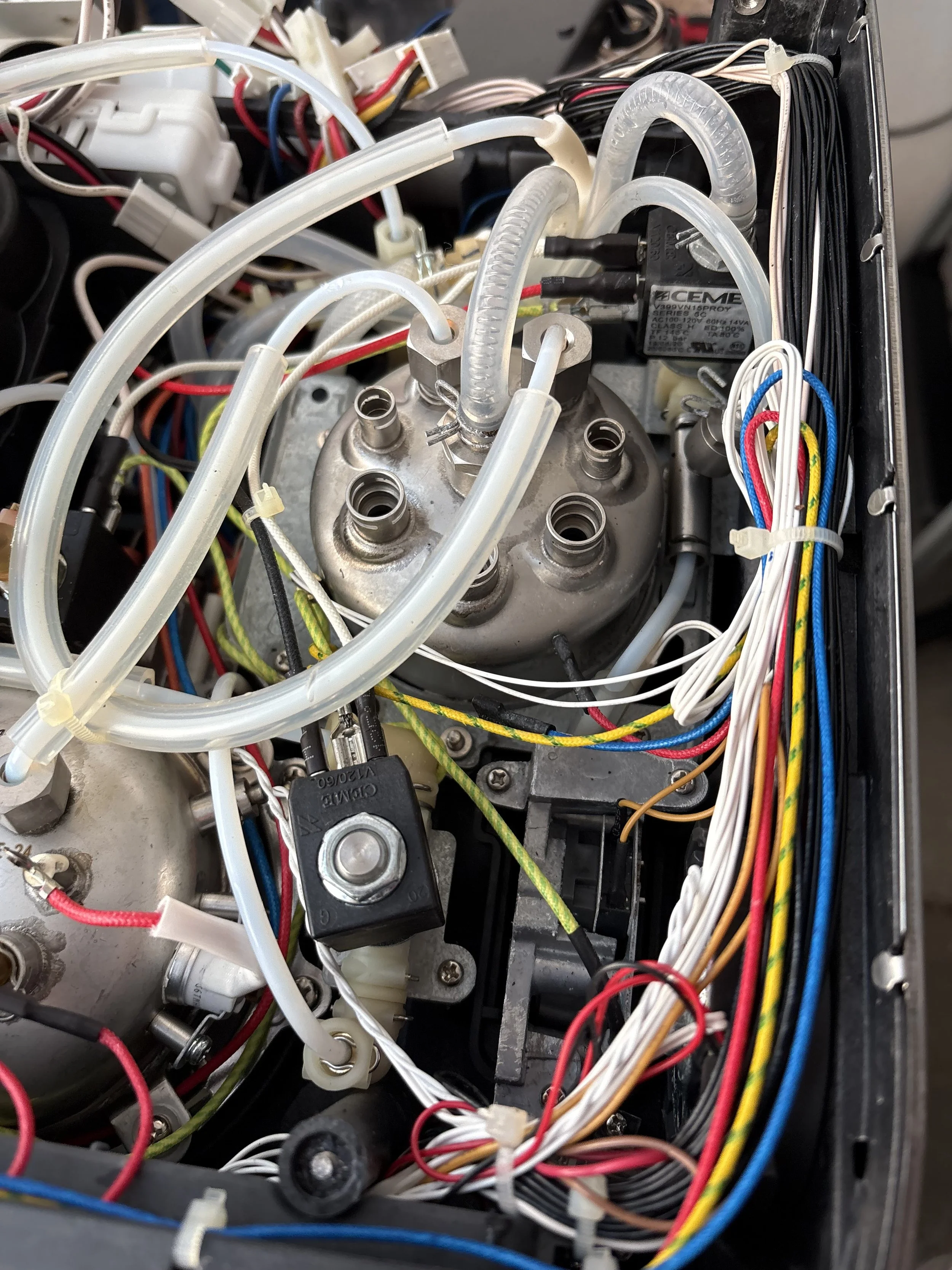 Close-up of the internal electronic components and wiring inside a machine, including tubes, wires, and a relay. Breville Oracle Internals.