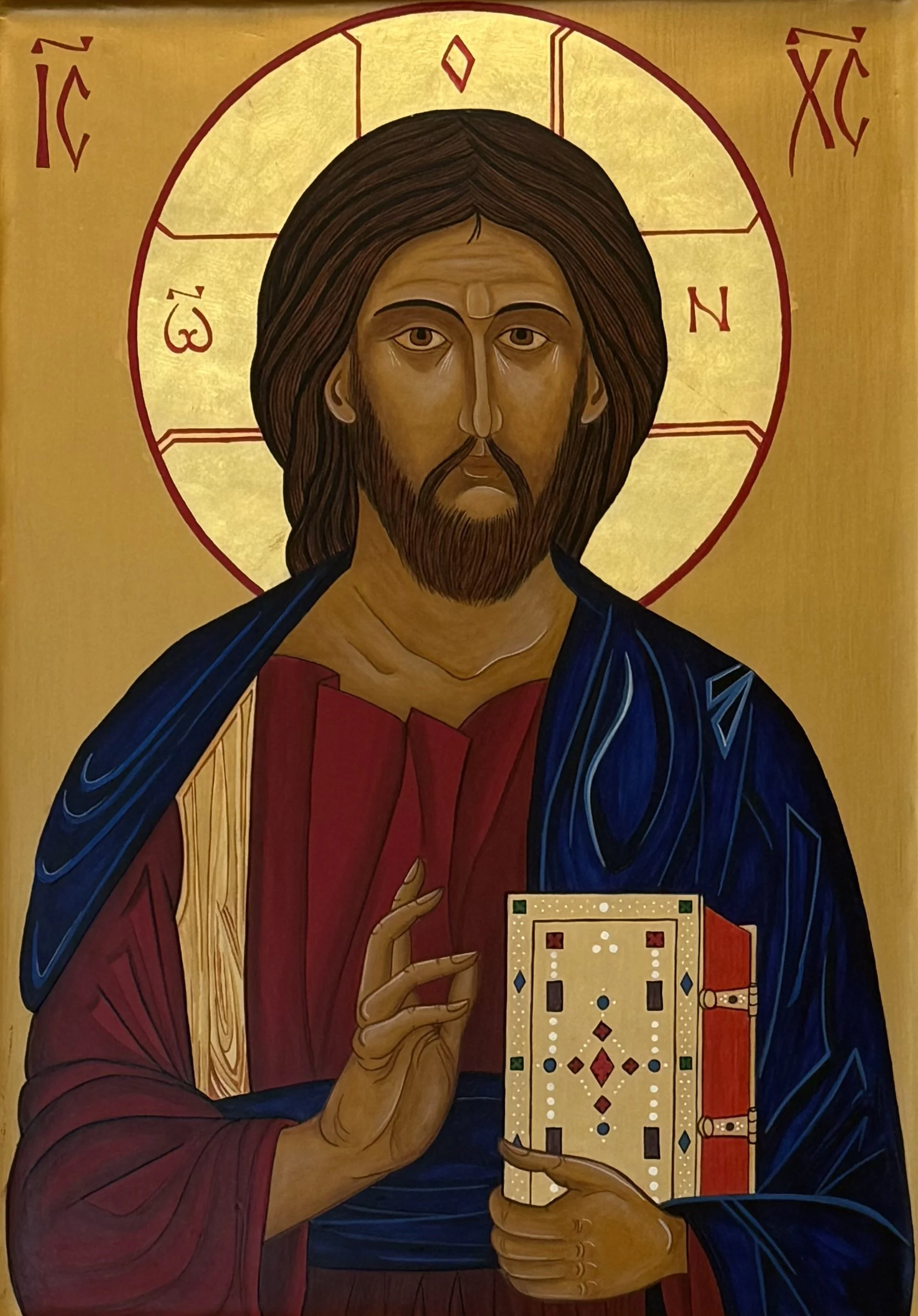A religious icon of Jesus Christ holding a Bible, with a gold background and red and blue clothing.