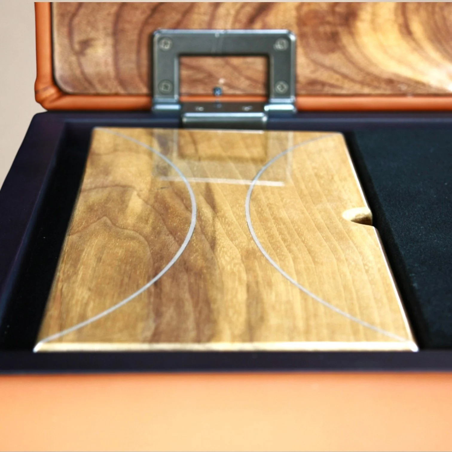 Close-up of a tabletop hockey game in a wooden box with a glass cover, showing the playing surface with painted ice and lines.