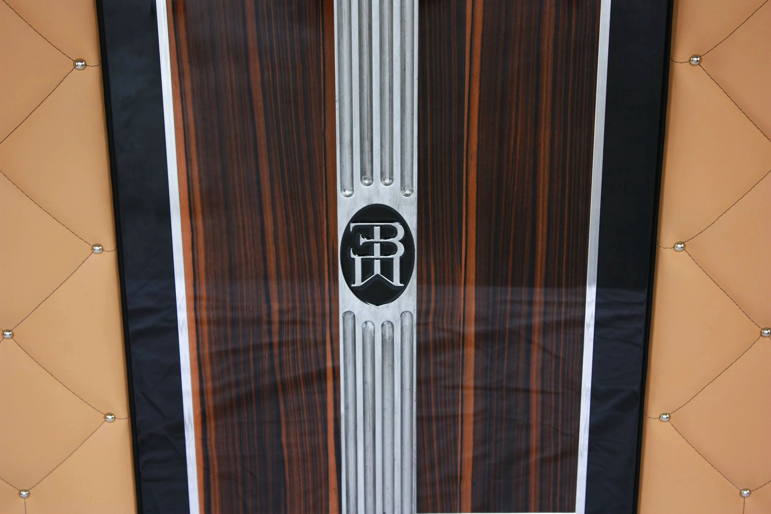 Close-up of a luxury car floor mat with wood grain design and a Bugatti logo in the center.
