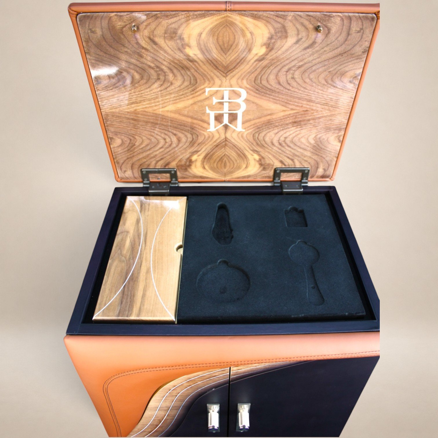 A wooden jewelry display case with a monogrammed lid, empty compartments, and a black velvet interior.